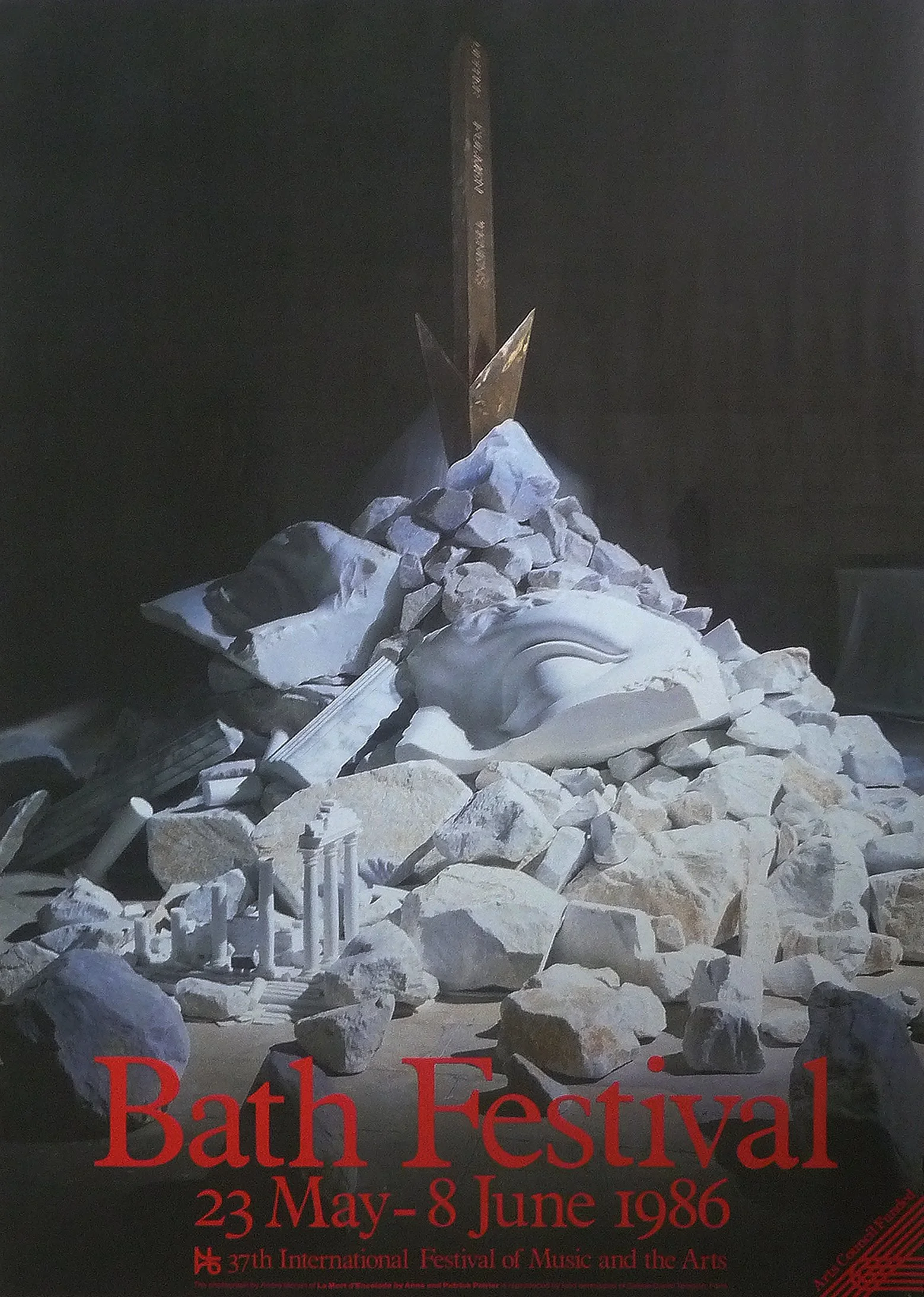 Poster for the 37th International Bath Festival, held from May 23 to June 8, 1986. The poster features an image of a sculpture with a large sword-like object piercing through its head, surrounded by smaller stone fragments.