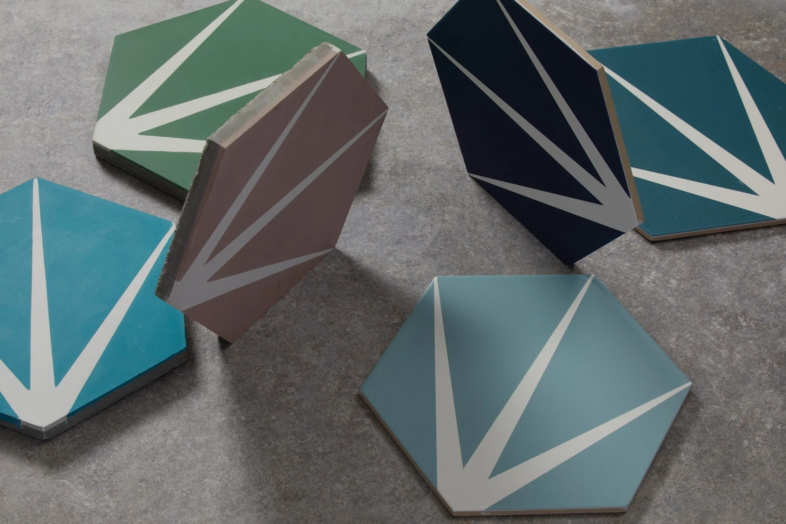 Colorful geometric tiles with a starburst pattern arranged on a gray surface.
