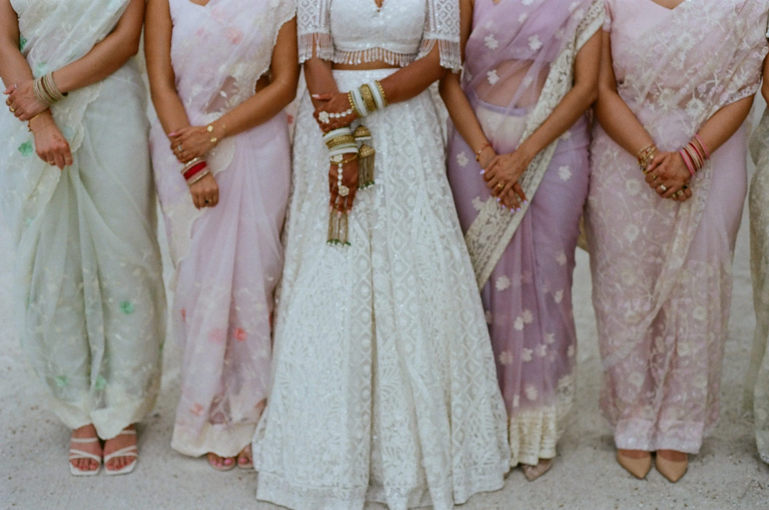 Close-up of women dressed in traditional Indian sarees, standing side by side with their hands folded in front.