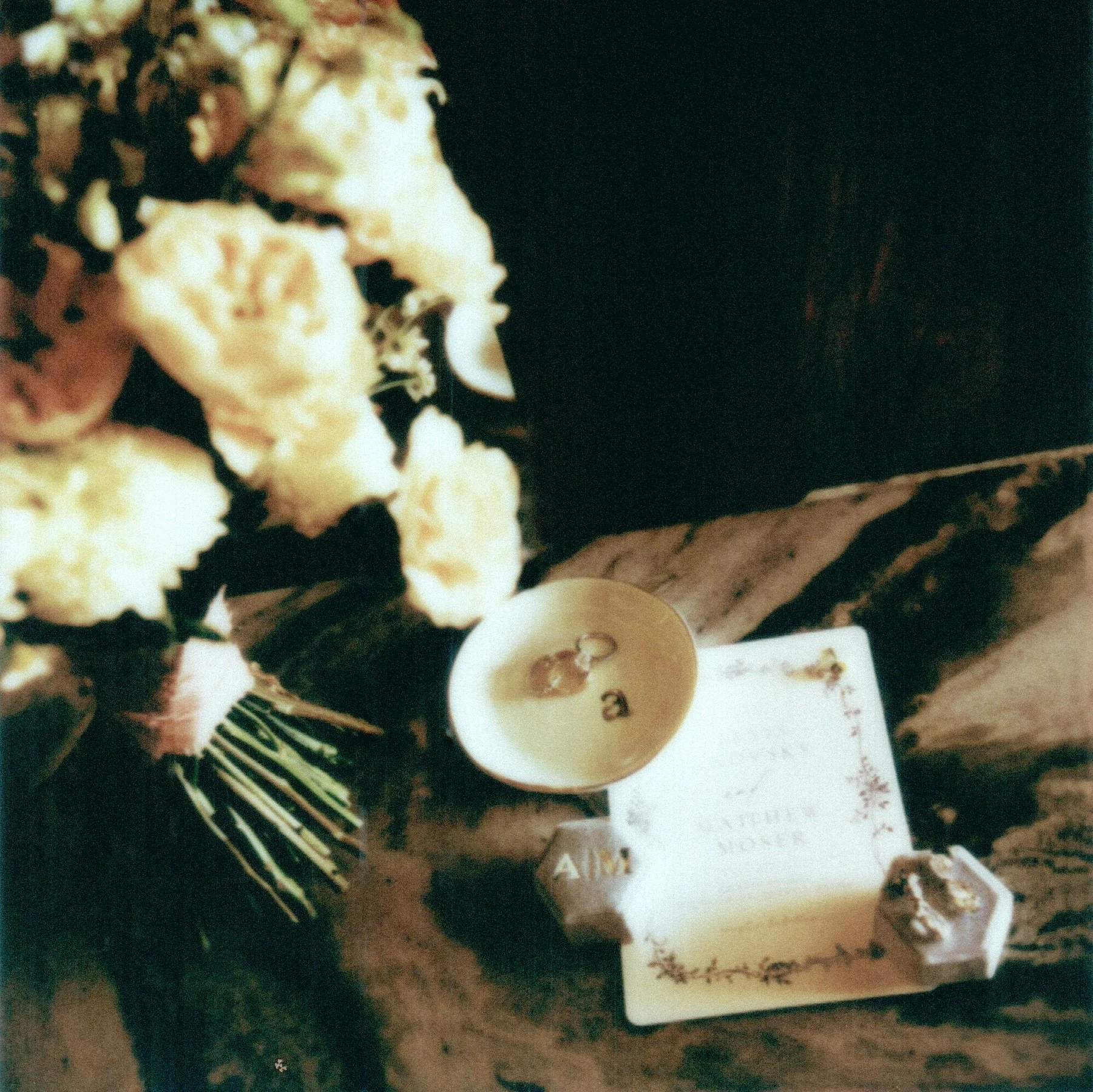 A gift box of chocolates wrapped with a ribbon, with a small card placed on top of the box and a small cup of coffee or tea.