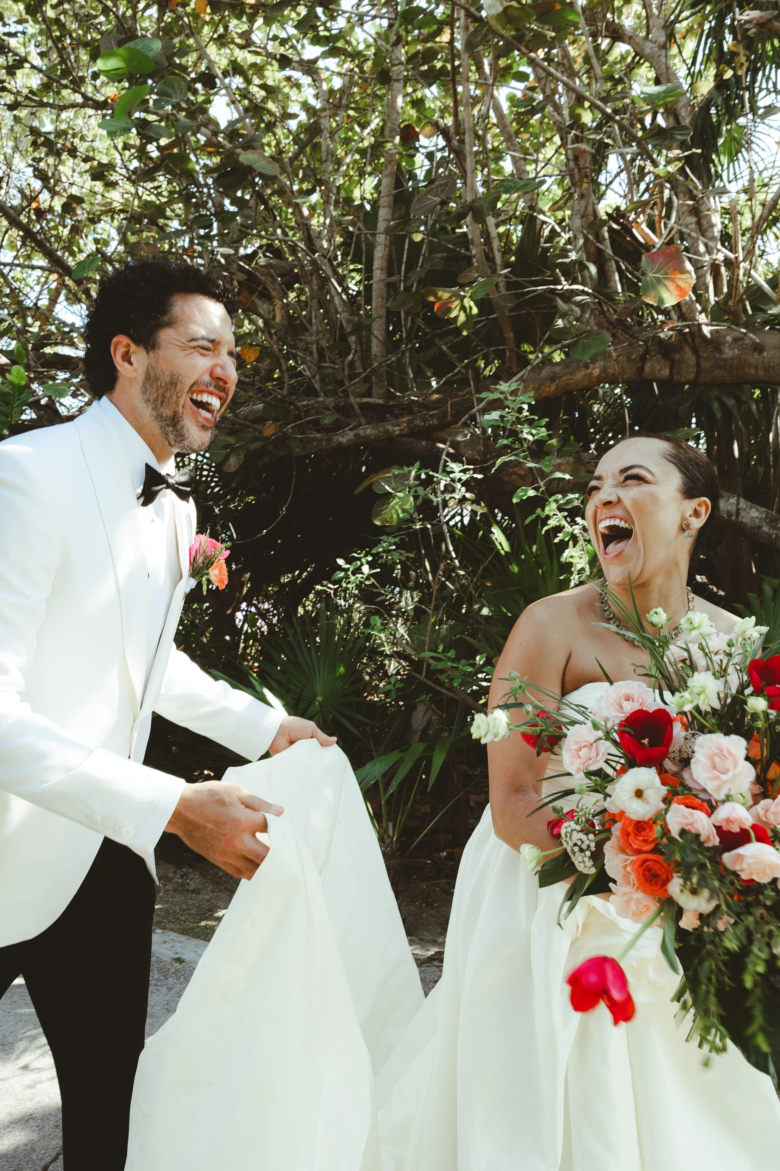 A bride and groom laughing during their wedding ceremony outdoors surrounded by lush green plants and trees in Dreams Sapphire.