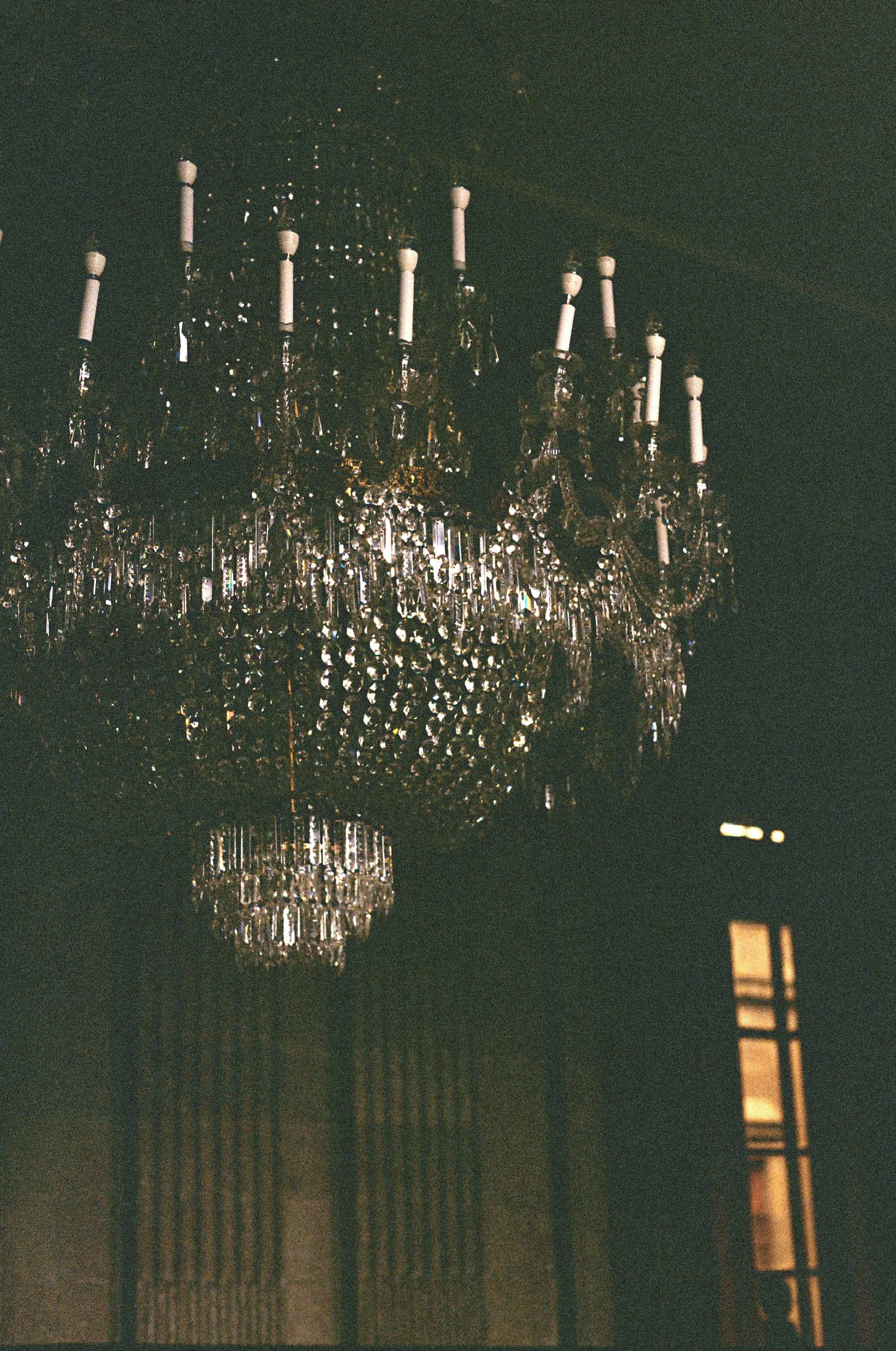 A clear view of a large, ornate chandelier hanging from the ceiling, with multiple crystal and glass decorations, in a dimly lit interior.