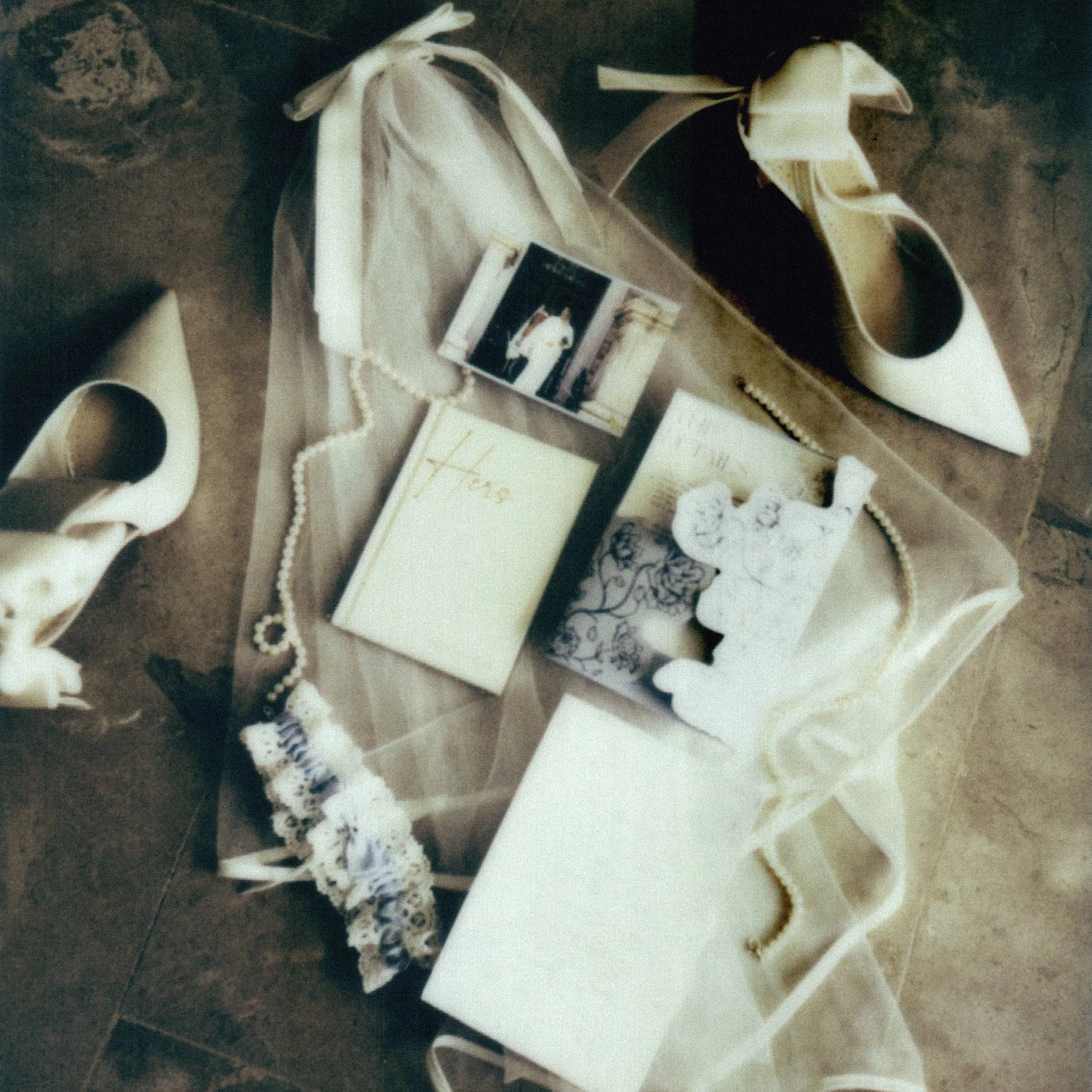 A collection of vintage items arranged on a surface, including white high heels, lace gloves, a pearl necklace, a small black card with a dog picture, a decorative box with the word 'Hope' on it, and a thank you card, with paper and fabric elements s