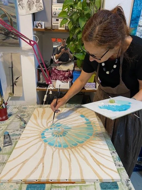 Miriam De Nardi sta dipingendo un quadro astratto con colori azzurri e beige in un studio di arte.