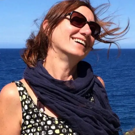 Donna con occhiali da sole che sorride con il mare sullo sfondo