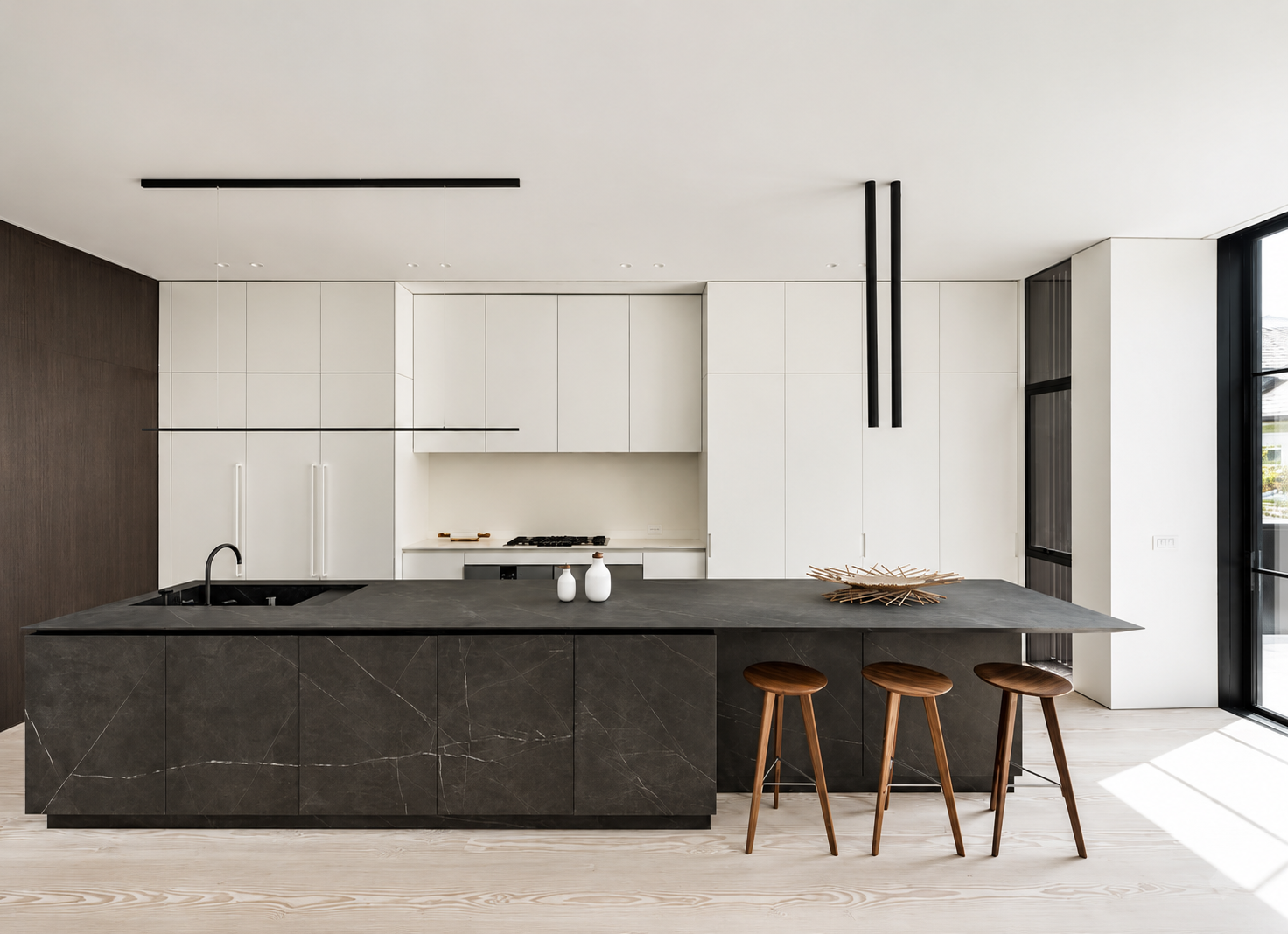 Cocina moderna con isla de piedra negra, gabinetes blancos, y sillas de madera.