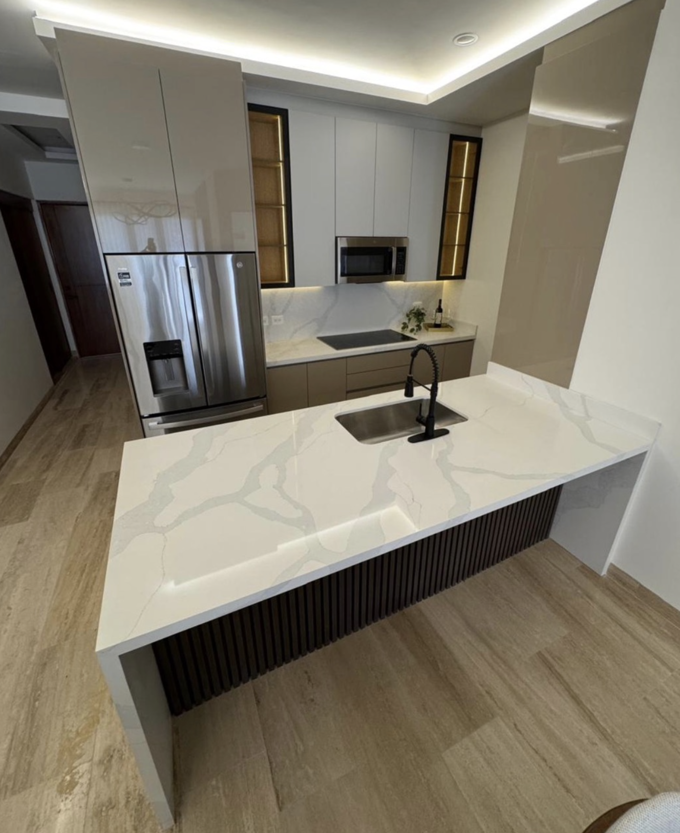Cocina moderna con isla y electrodomésticos de acero inoxidable.