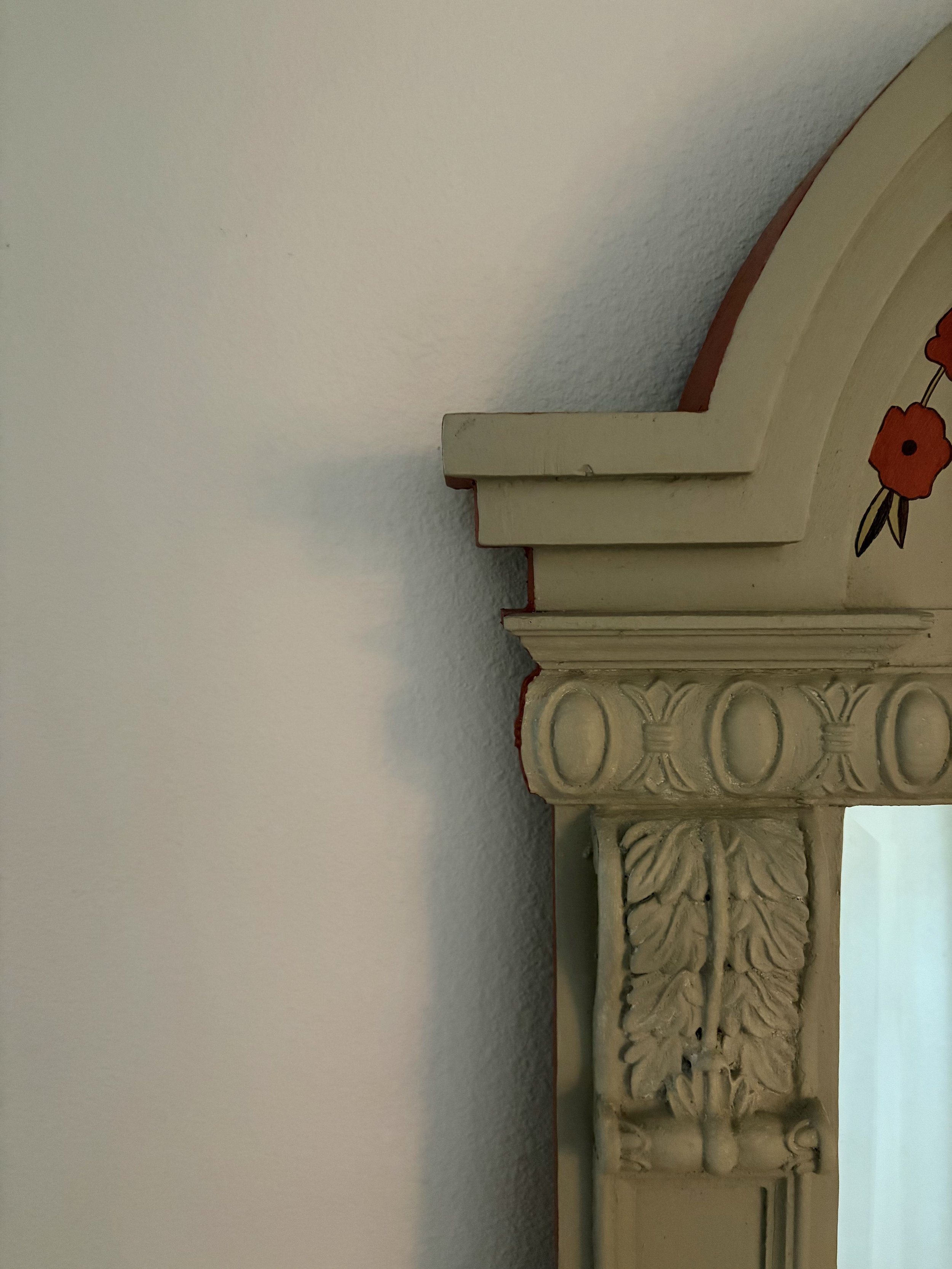Close-up of elaborate carved stone or wood architectural detail, possibly a capital or decorative column, with floral and geometric patterns, against a plain wall background.