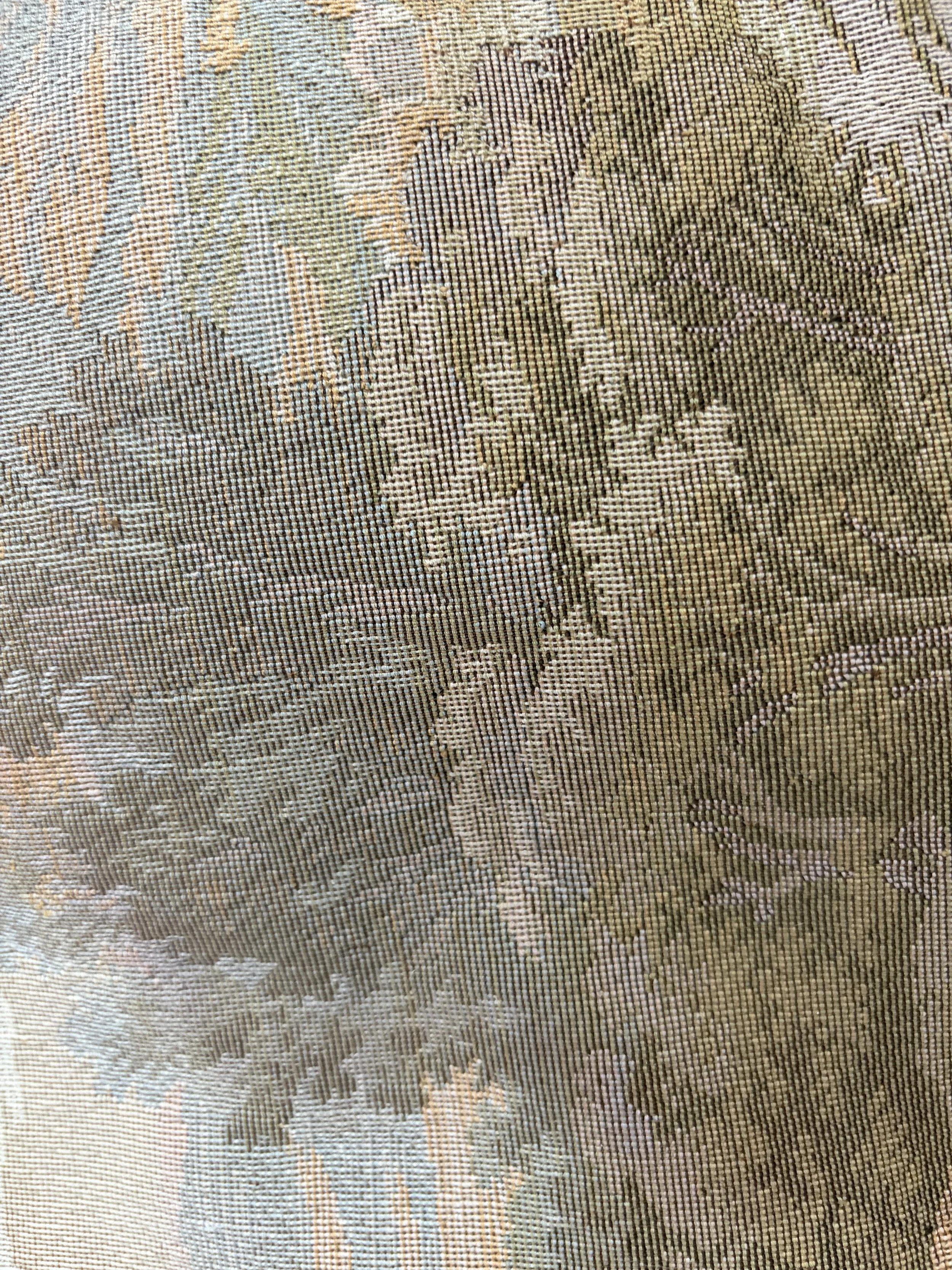 Close-up of a fabric pattern with floral and abstract designs in beige, green, and pink tones.