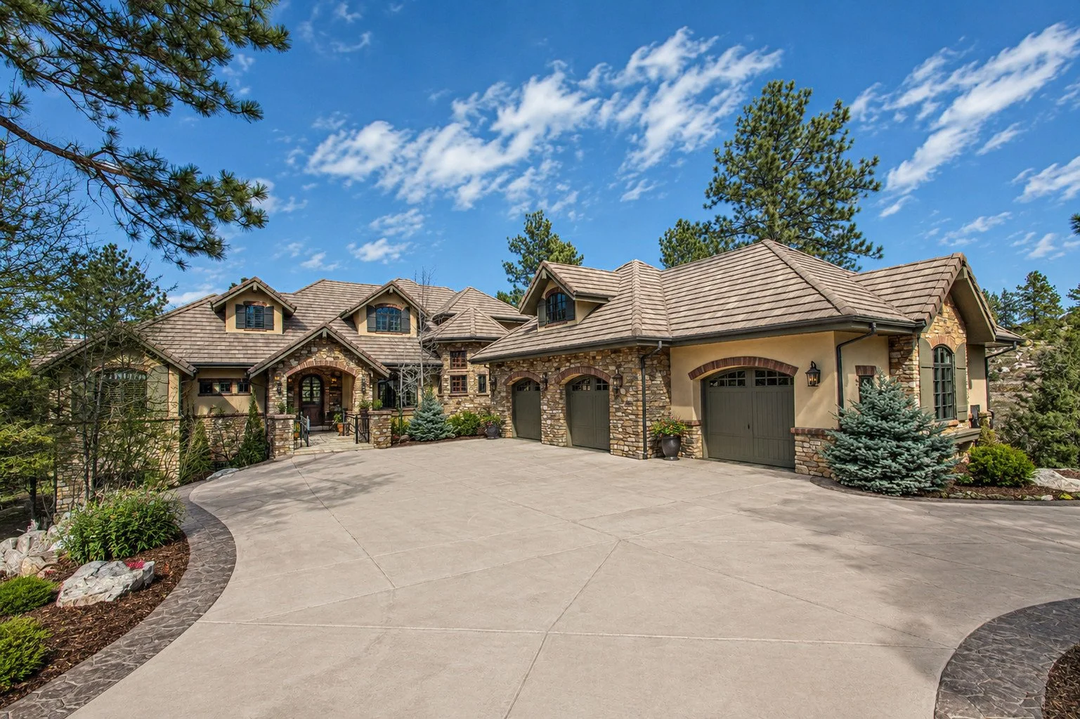 European custom home with stone and stucco exterior, multiple gables and attached garage, Castle Rock, Colorado