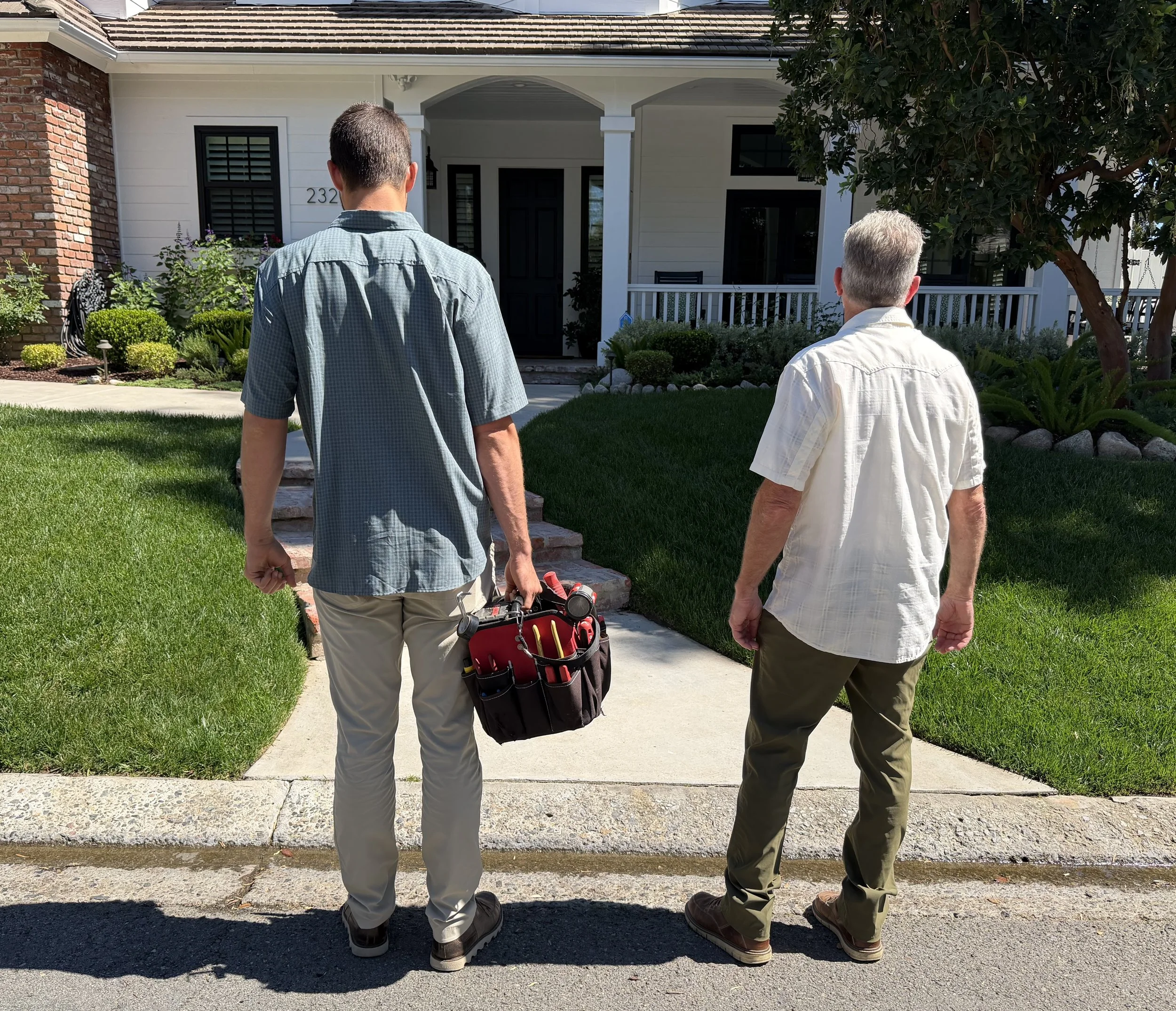two male surf city audio visual technicians holding tools walking into a house orange county