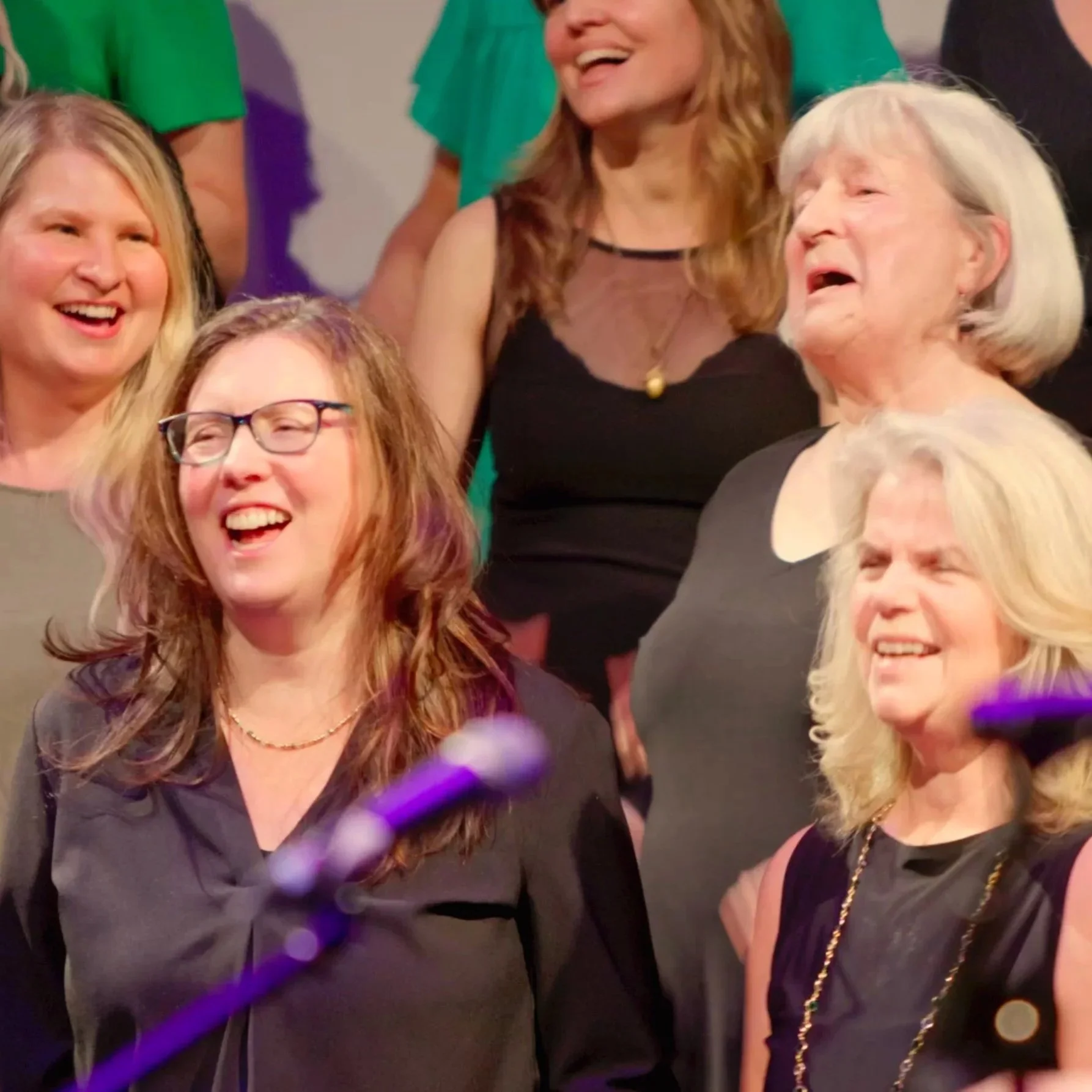 A group of women smiling and laughing during a social event or gathering, dressed in casual and semi-formal attire.