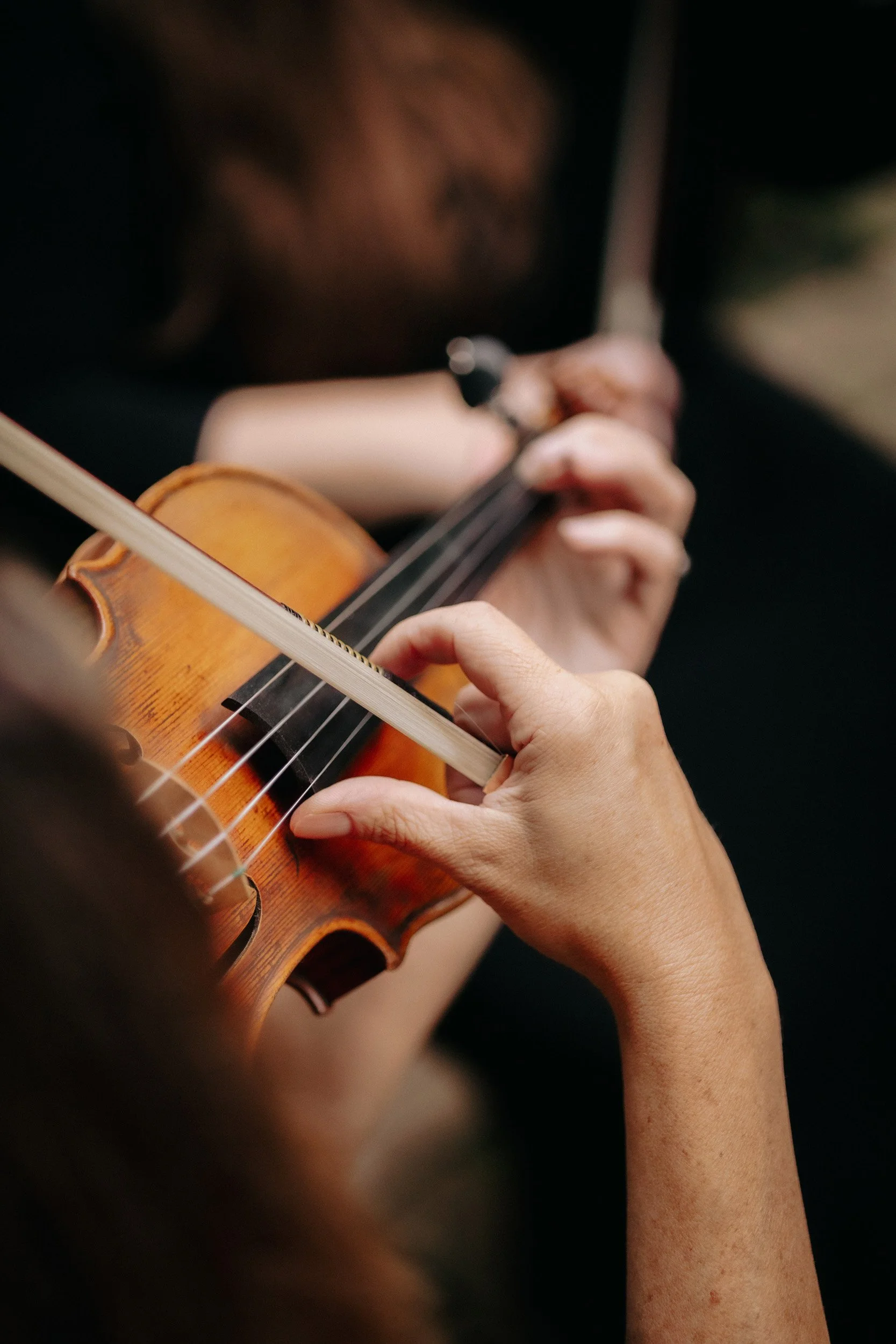 Close-up of a person playing a violin, focusing on their hands and the instrument.