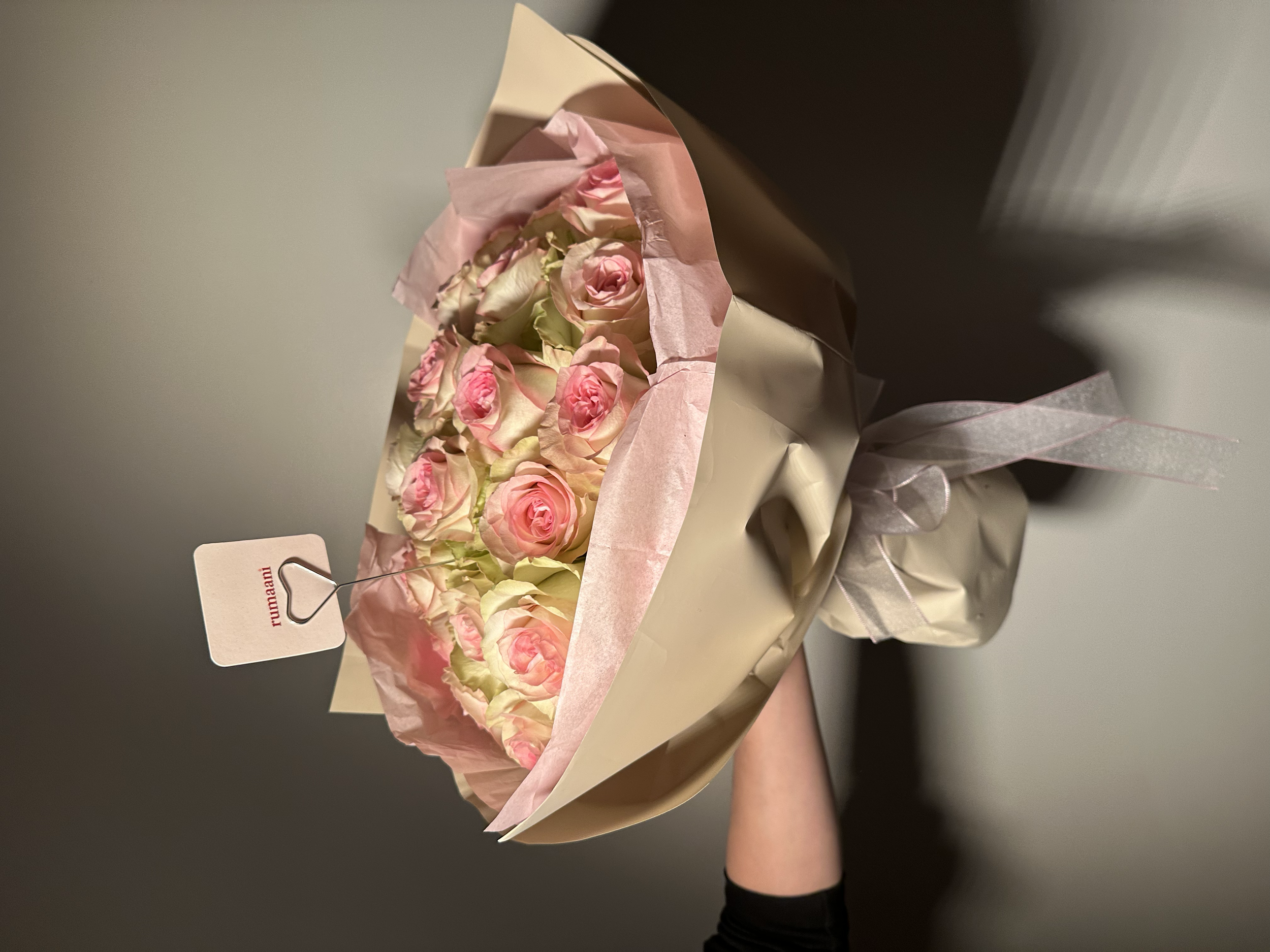 A bouquet of pink and cream roses wrapped in pink and cream paper.