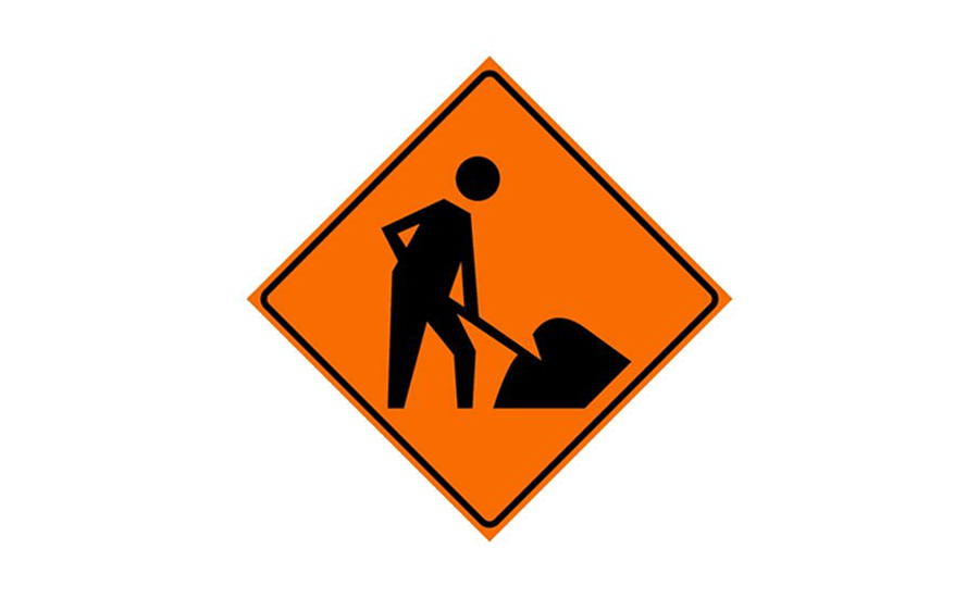Construction worker digging with shovel on orange warning sign.