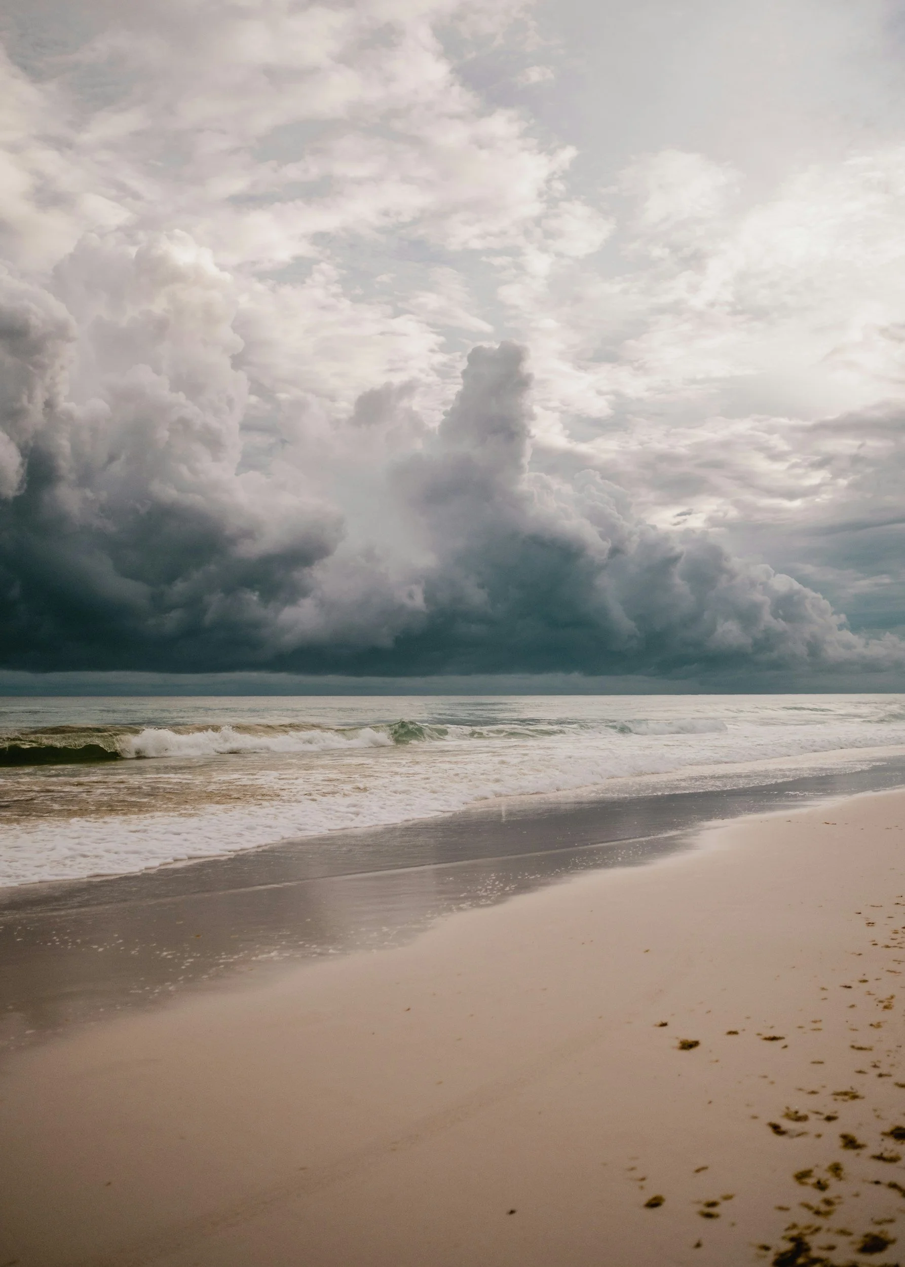 Dark storm clouds over a peaceful Florida beach, highlighting changing coastal weather and hurricane preparedness.