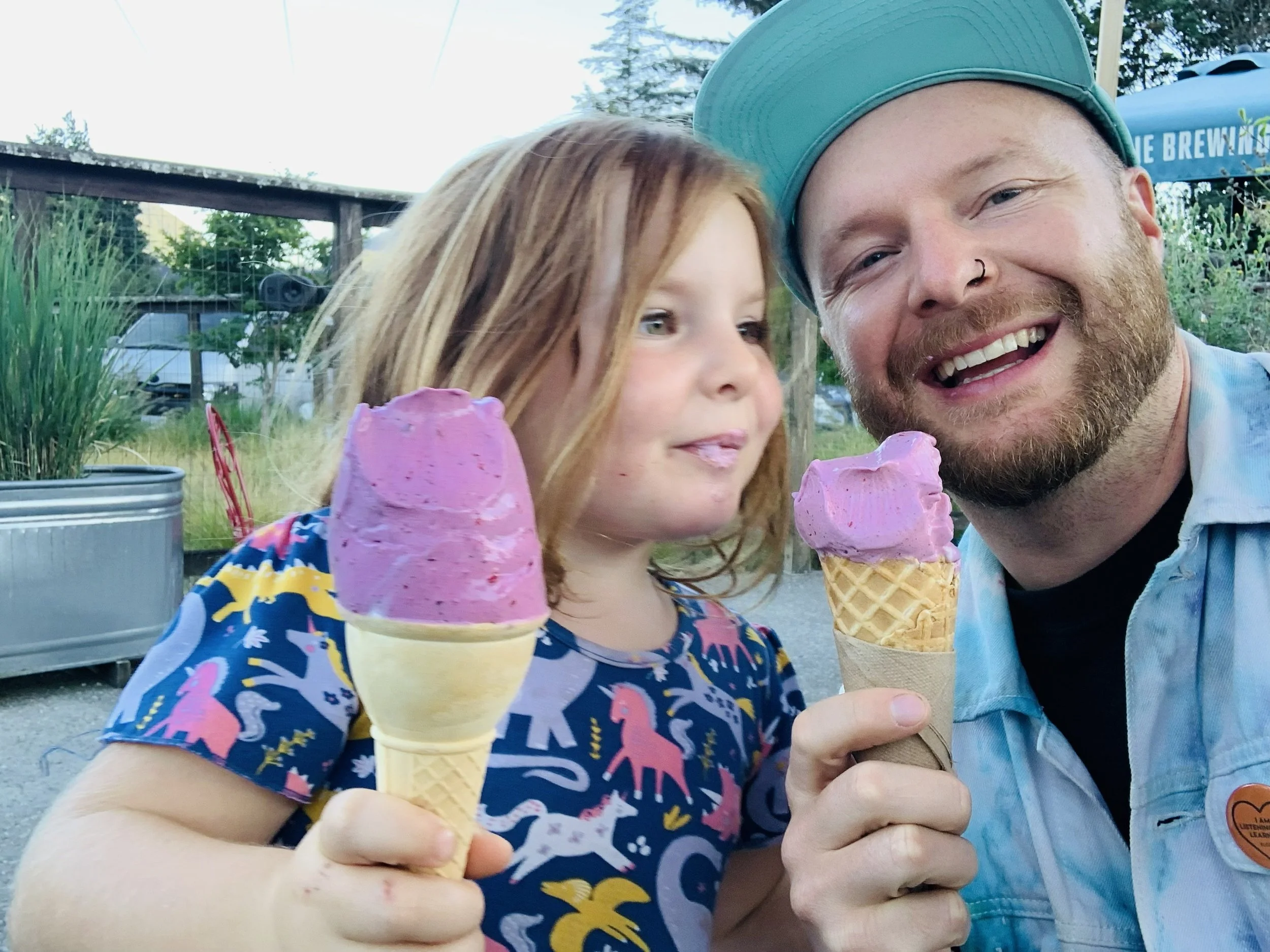Sean Easton and his daughter Roxy, enjoying ice cream cones outdoors, smiling at the camera.
