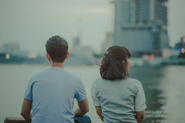 Couple sitting side by side overlooking the water, reflecting connection and communication in a relationship.