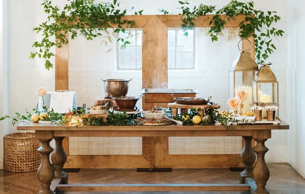 Rustic buffet table with copper serving pieces, lanterns, and greenery