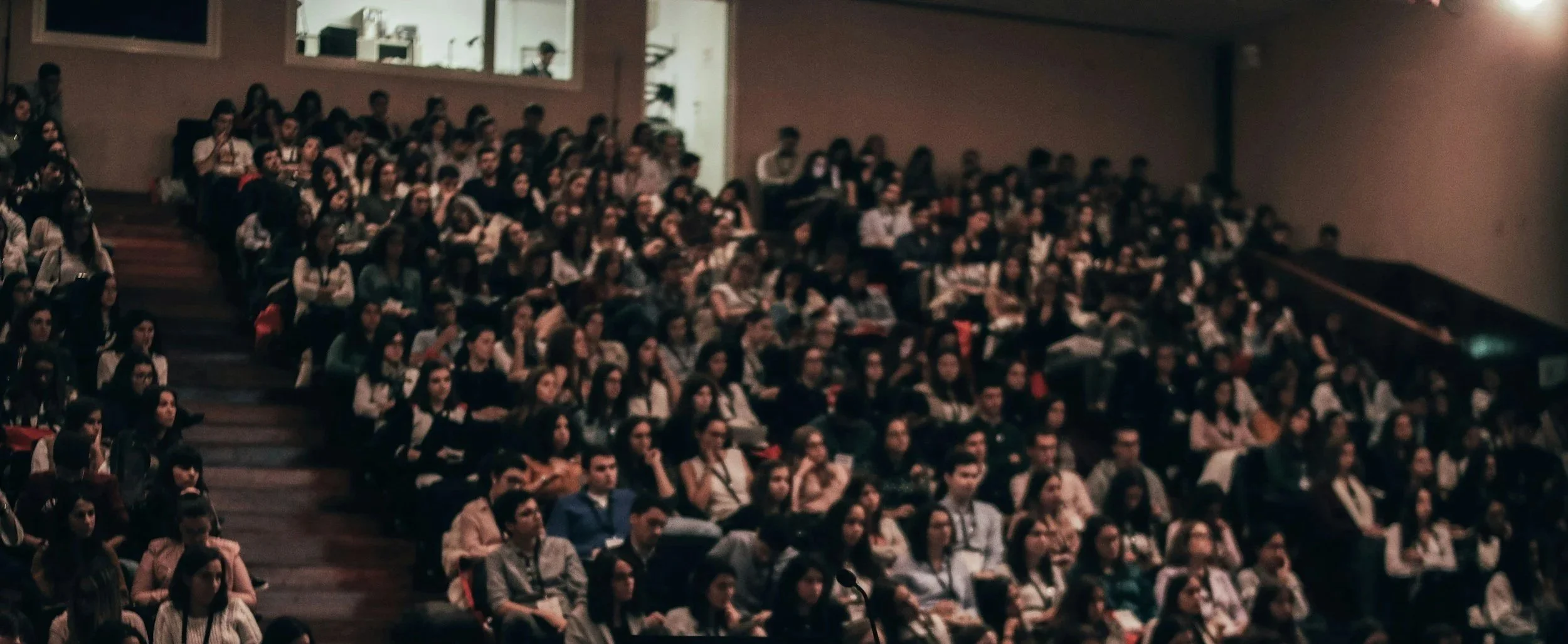 A large group of people seated in an auditorium, watching a presentation or performance.