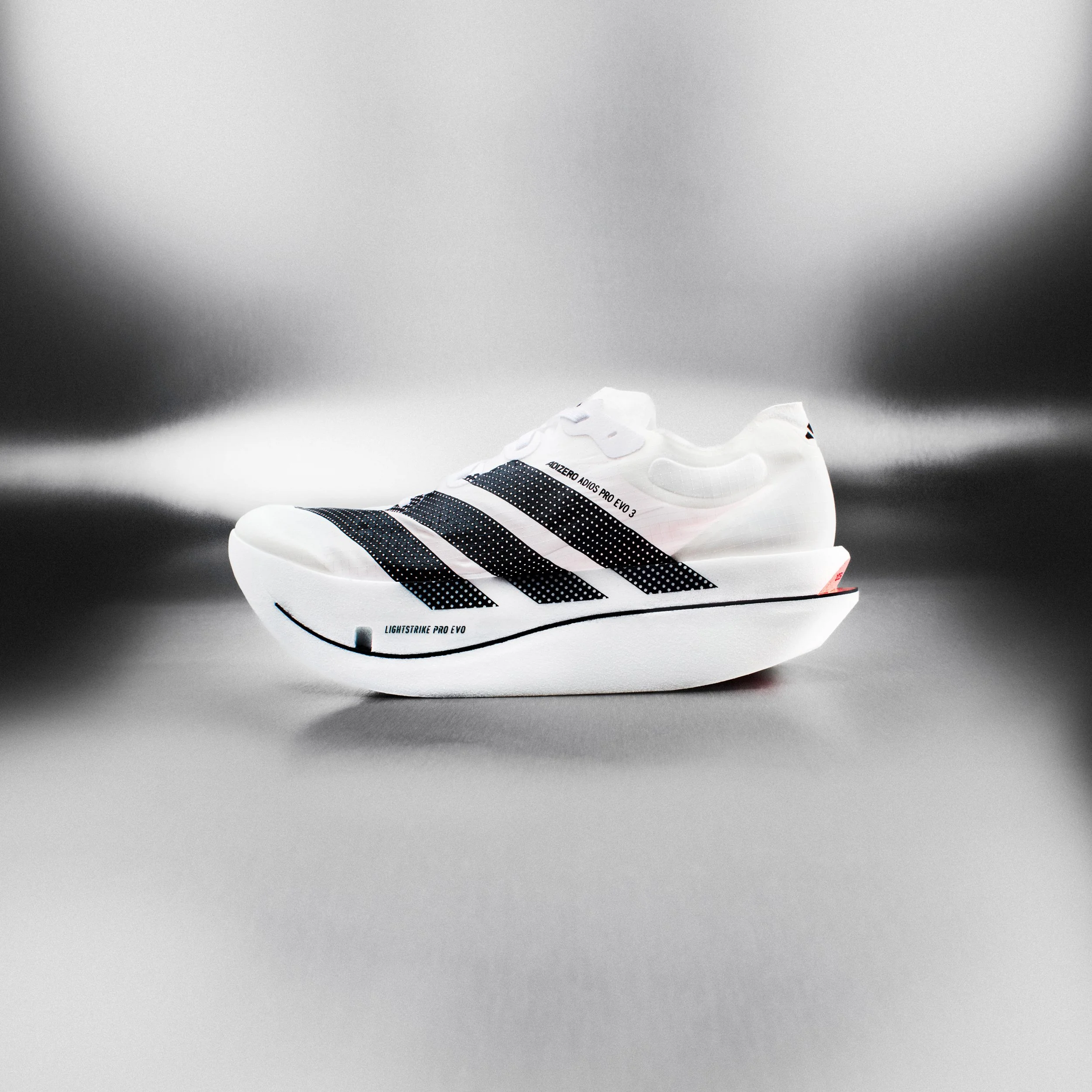 A white athletic sneaker with black stripes and the text "ADIZERO ADIOS PRO EVO 3" printed on the side, positioned on a plain white surface with a plain gray background.