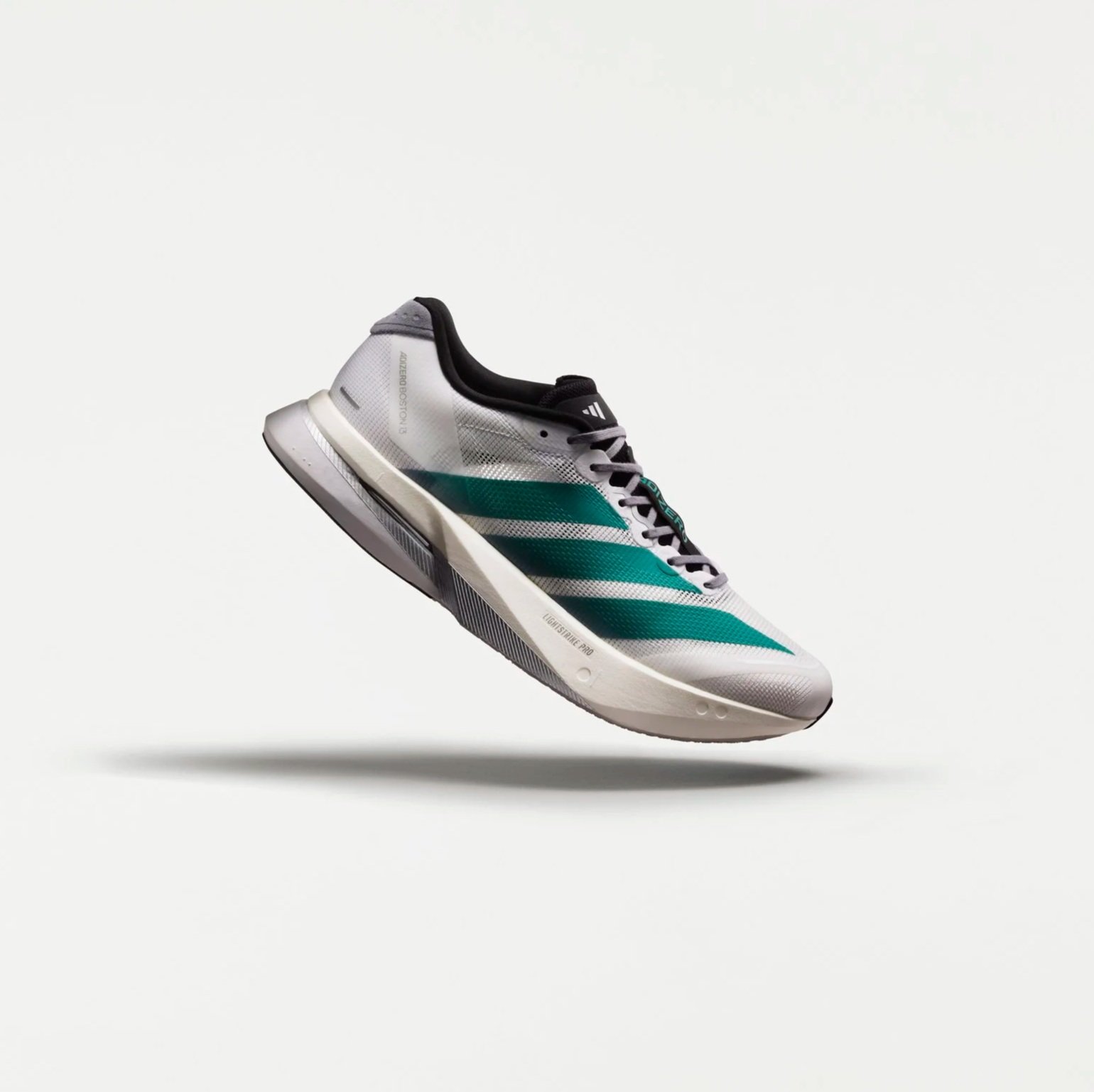 A white and teal Adidas running shoe floating against a white background.