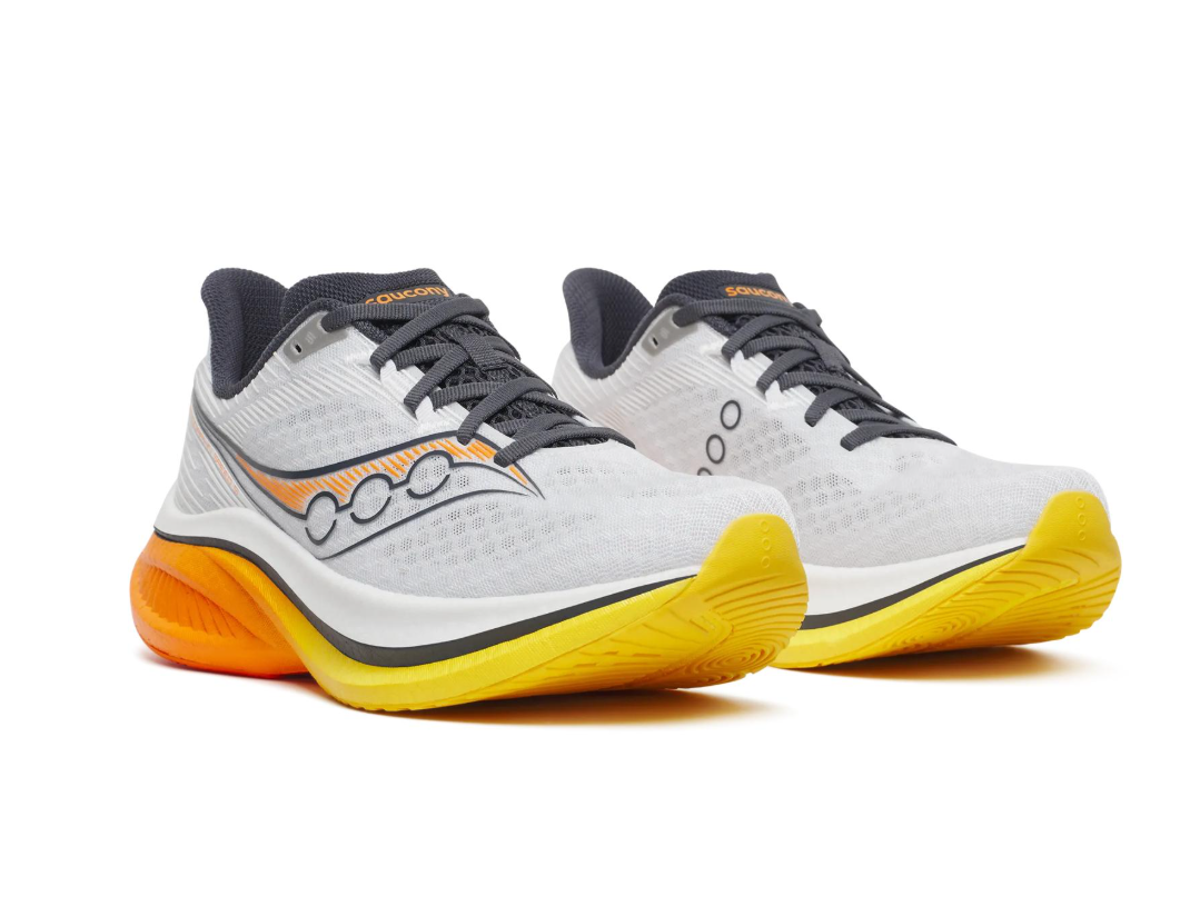 A pair of gray and yellow running shoes with black accents and orange details, displayed against a white background.