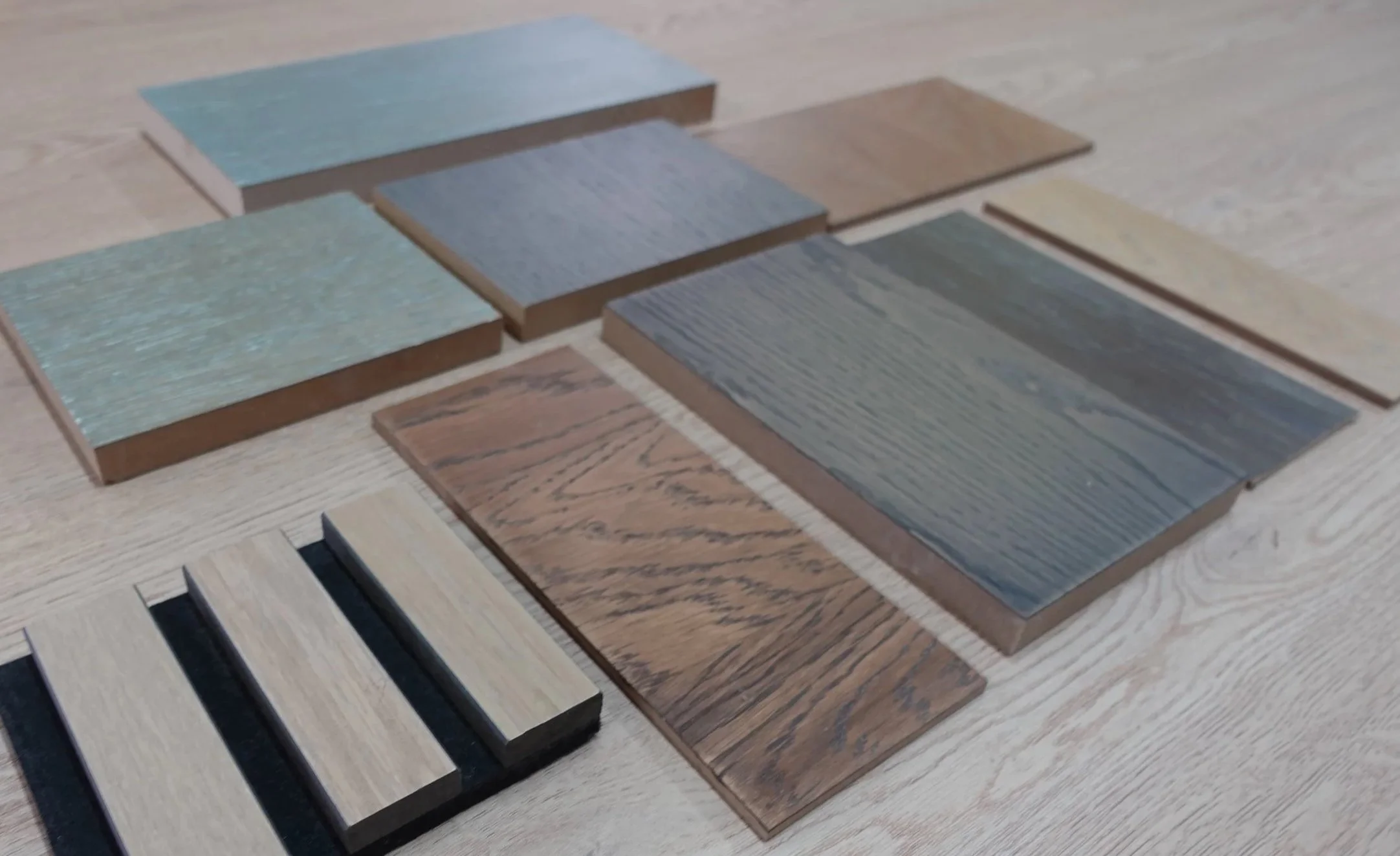 An array of materials of different wood finishes on a desk.
