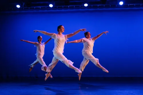 Three Brattleboro School of Dance students leaping onstage together during a performance
