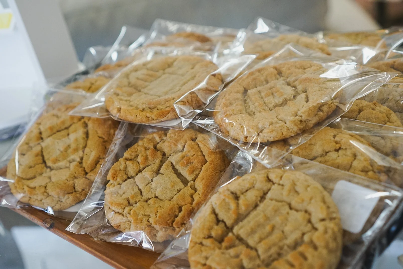 Several packaged oatmeal cookies with a crumbly appearance stacked on a wooden surface.