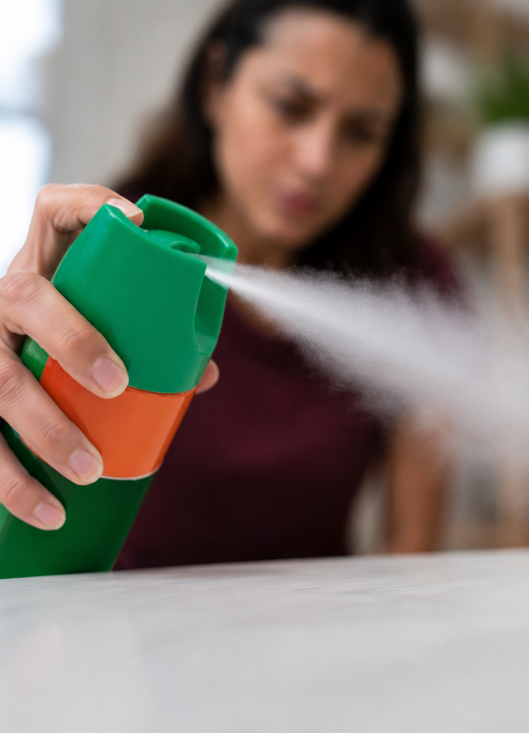 a worried woman spraying pests in her home
