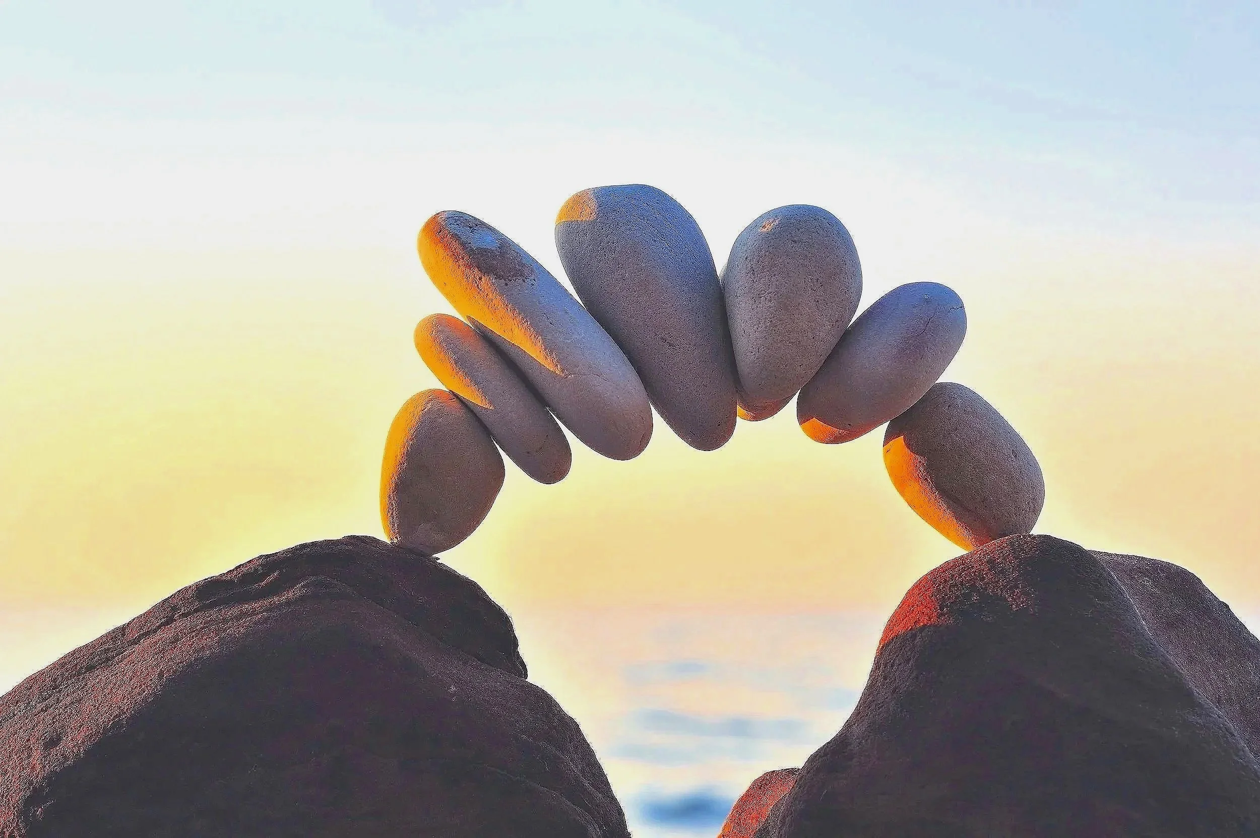 Close-up of a person's hand in a fist raised against a sunset sky with clouds, with the light creating a warm glow on the fingers.