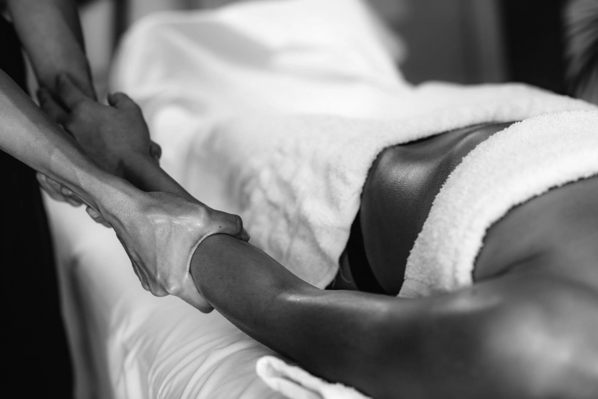 A person wearing a glove gently holding the hand of another person, with a towel or blanket underneath. The scene appears to be in a clinical or care setting.