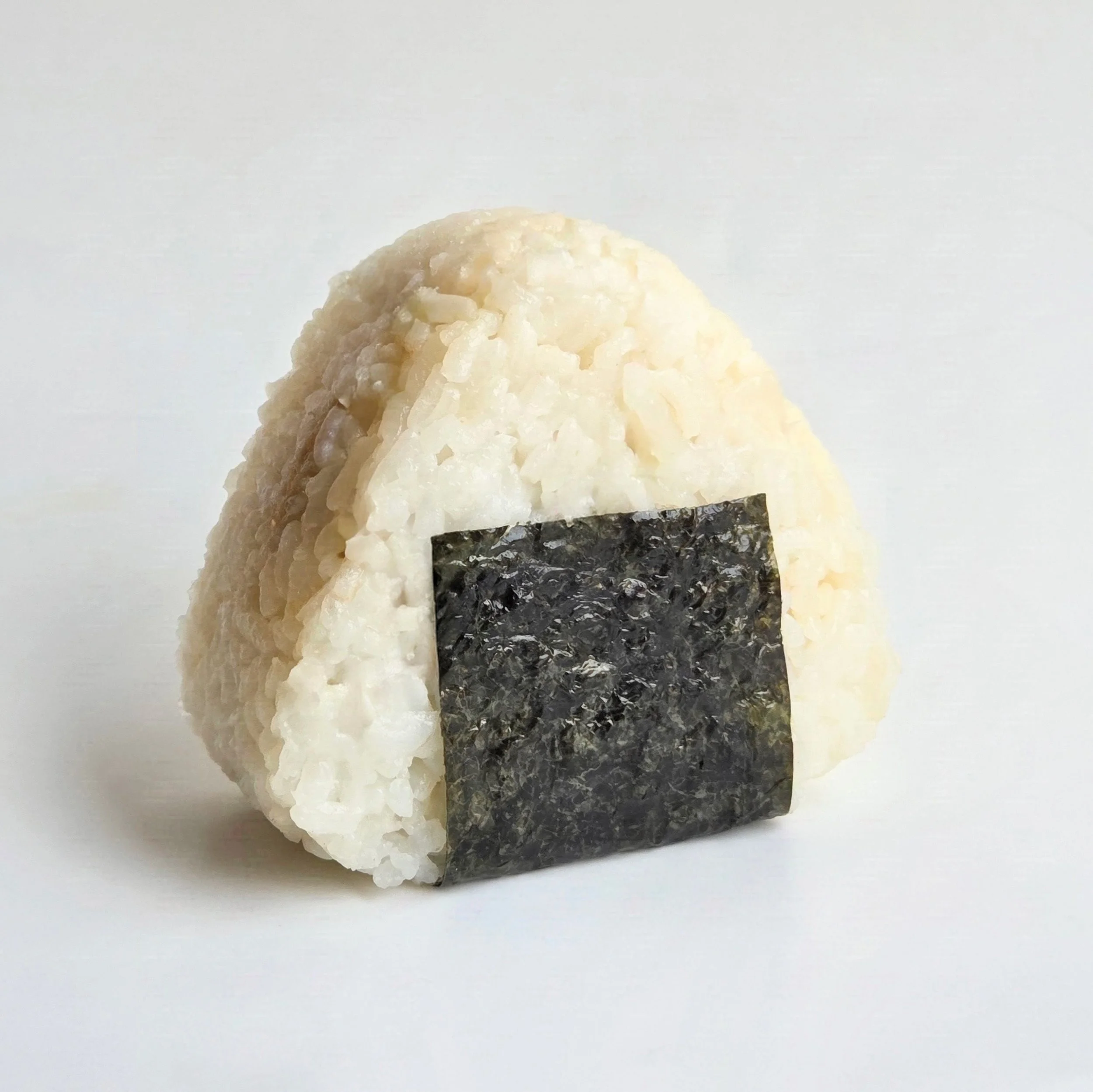 Close-up of a maki sushi roll with white rice, nori seaweed, and possibly fish or other ingredients inside, on a plain white background.