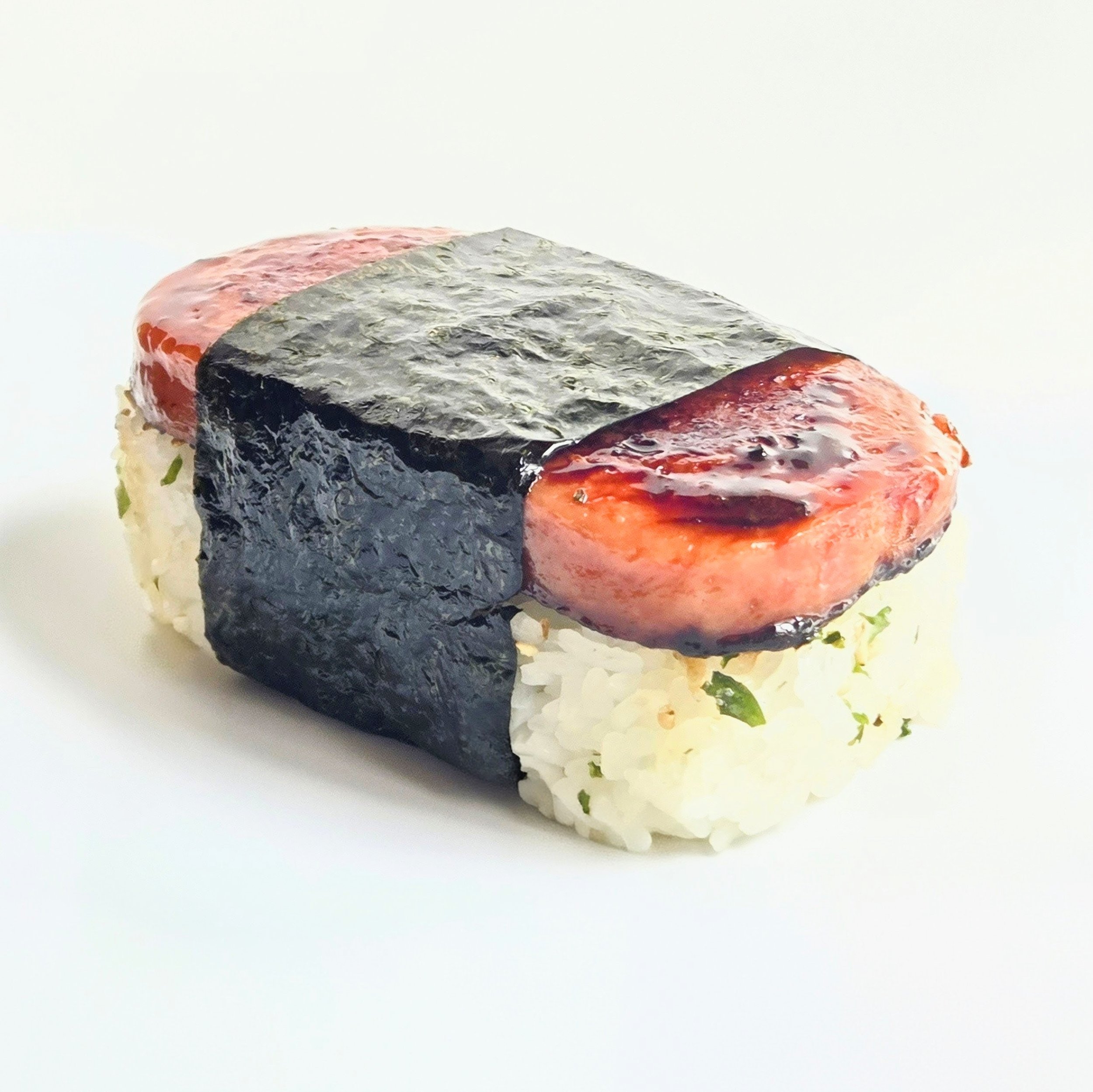 Close-up of a piece of sushi with rice, avocado, and fish, wrapped with seaweed, on a white background.