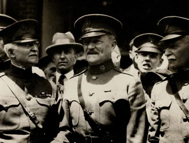 Black and white photograph of multiple military officers in uniform and peaked caps, engaged in conversation.