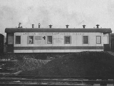 A black and white photo of a mobile medical unit labeled 'American Expeditionary Forces Siberia,' with windows and a door, parked on a dirt area.