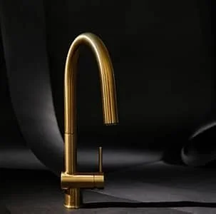 A gold kitchen faucet against a dark background.
