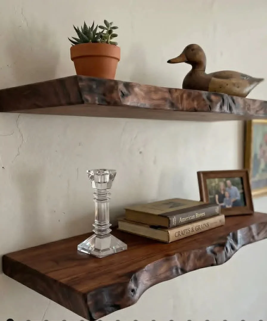 Two wooden floating shelves decorated with books, a photo frame, a glass candle holder, a potted plant, and a wooden duck figurine.