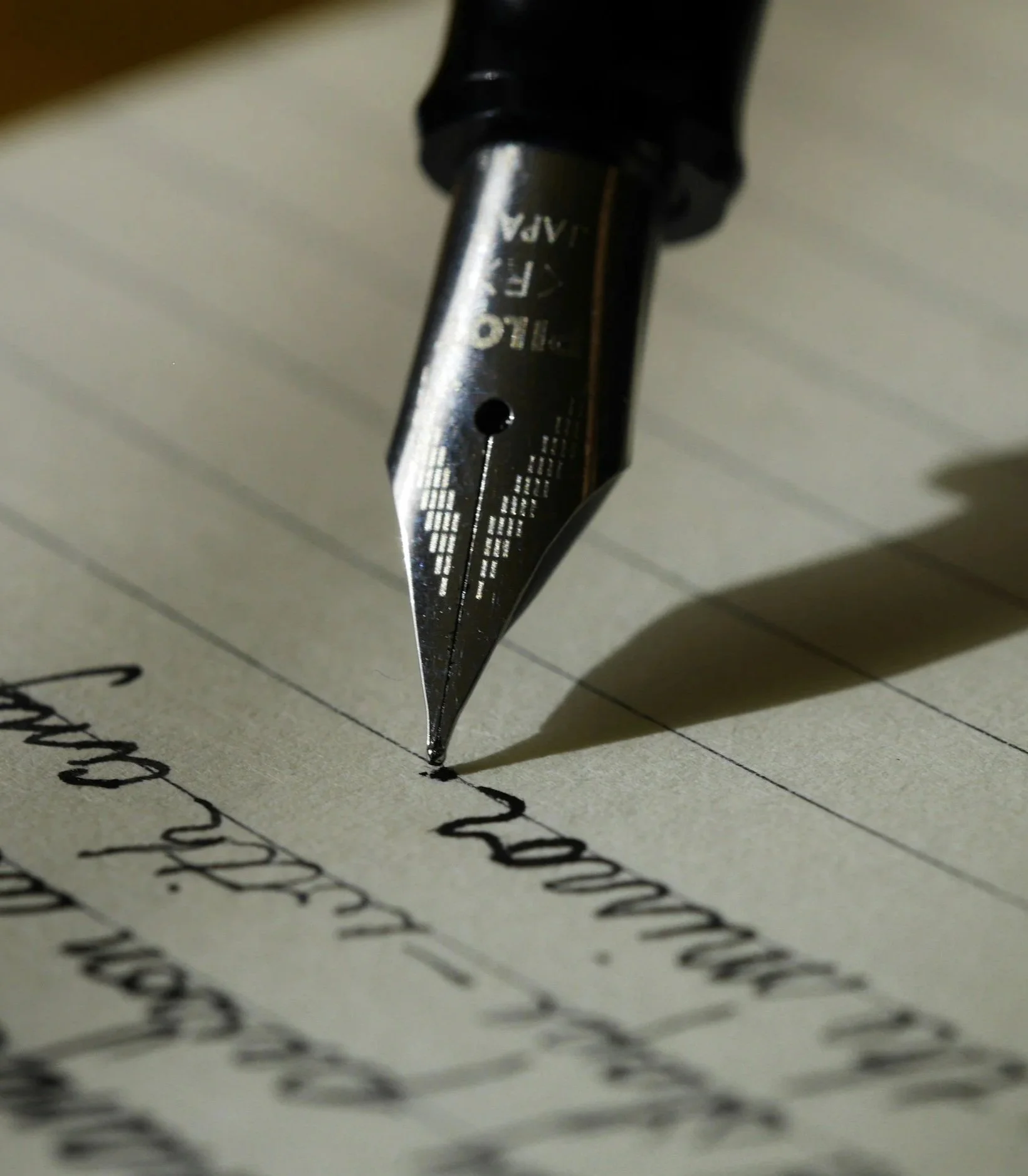 Close-up of a fountain pen writing on lined paper.