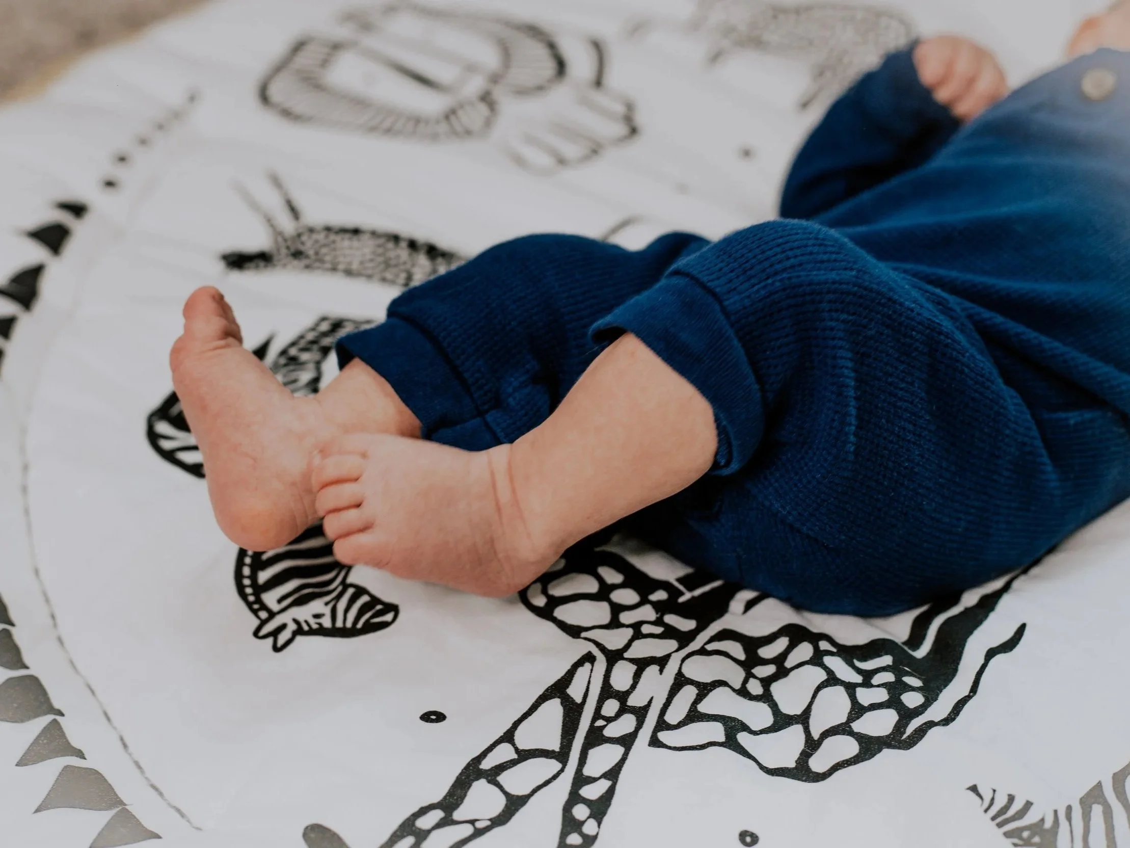 Close-up of a child's hand holding an adult's hand over a black-and-white illustration of a dinosaur printed on paper.