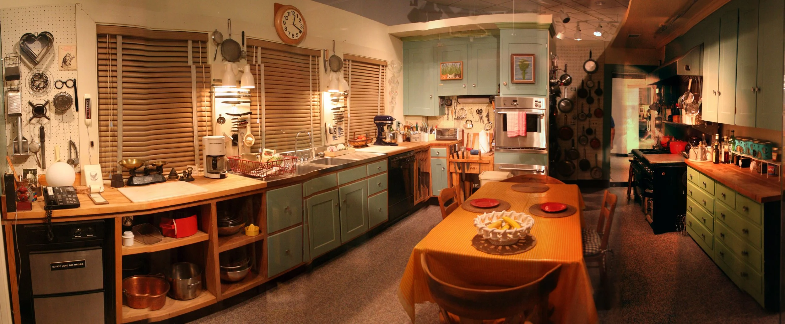 Julia Child’s preserved kitchen with green cabinets, cookware, worktables, and cooking tools.