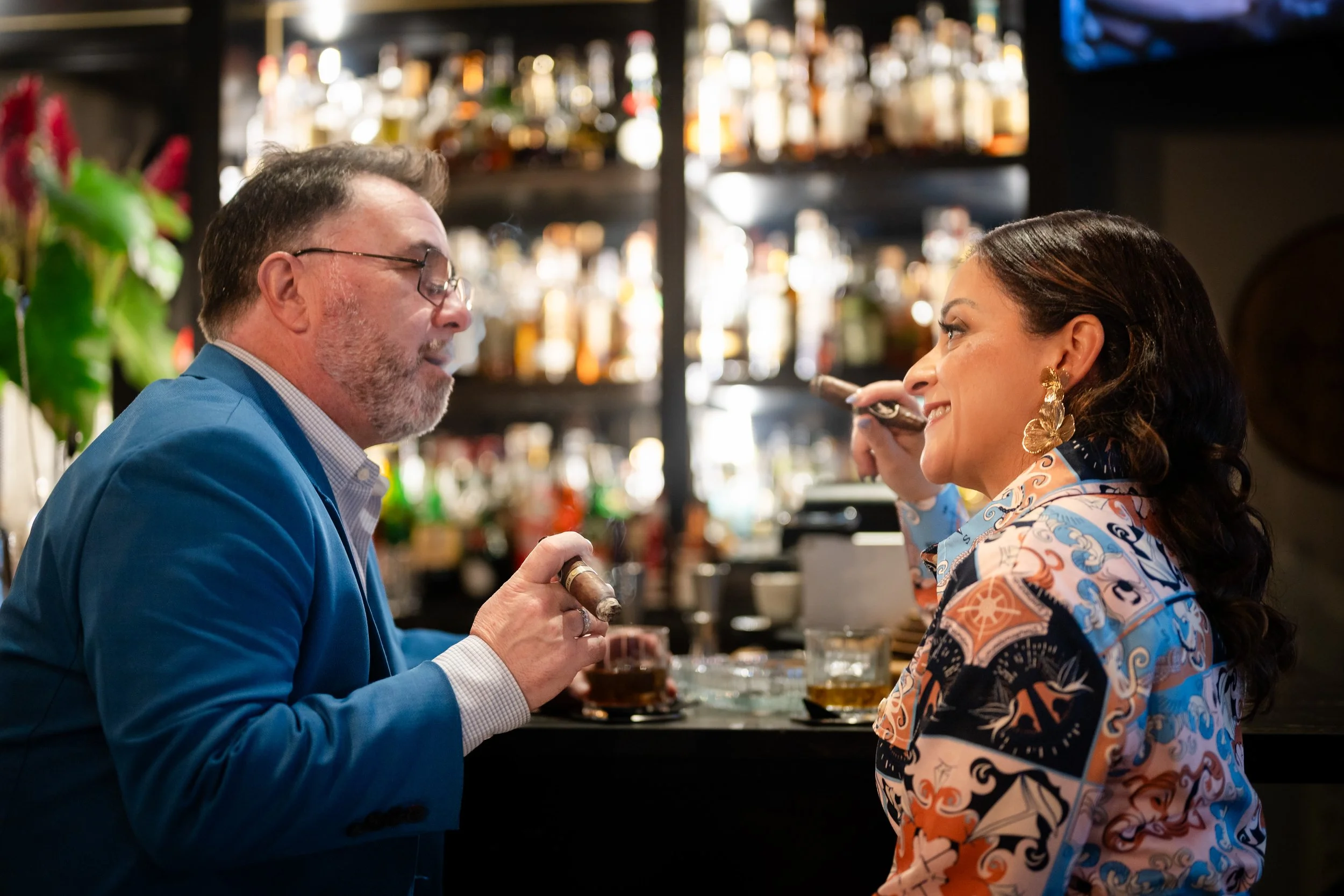 Tania Lopez sharing a cigar conversation with a guest in an elegant lounge.