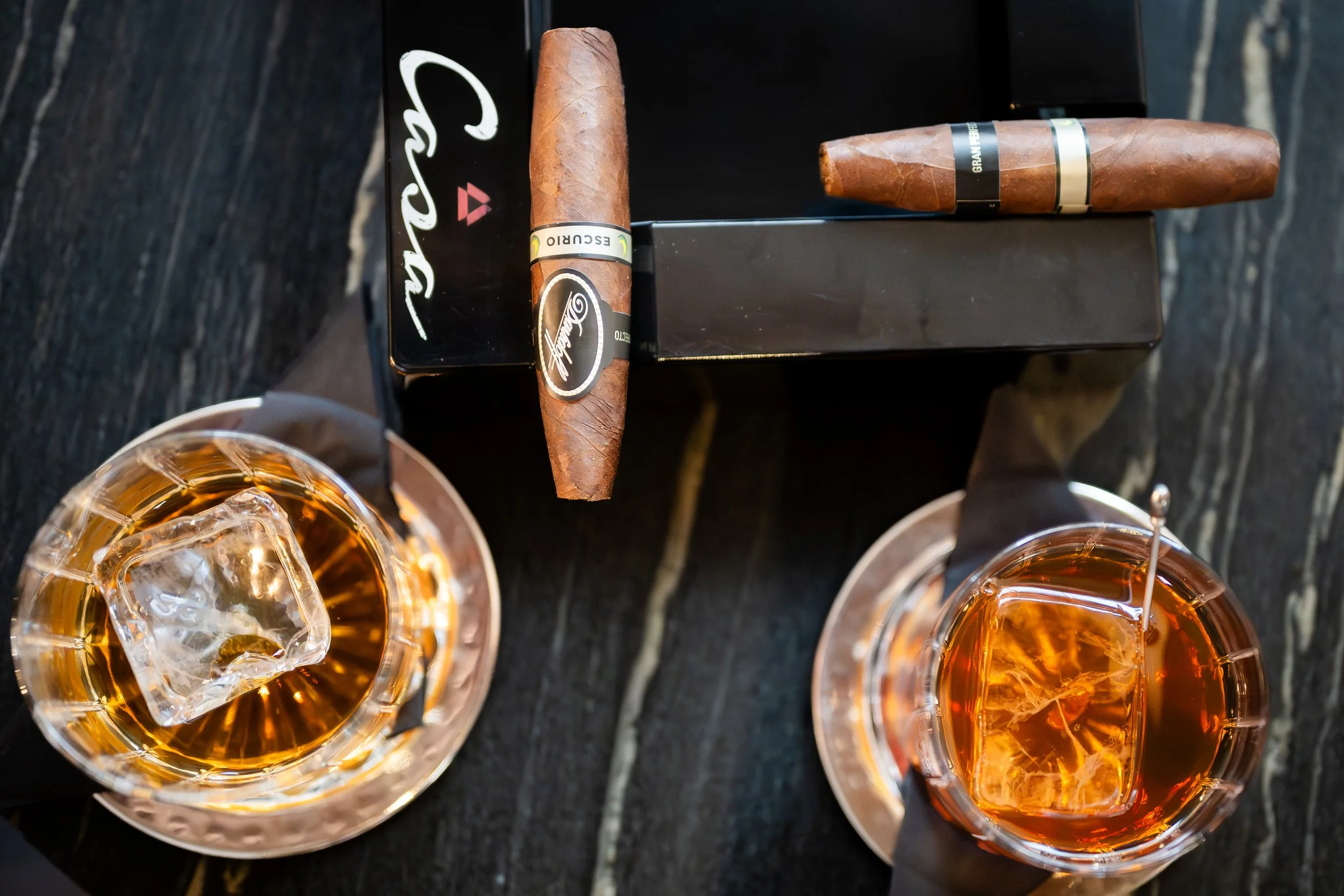 Glasses of Ron del Barrilito rum paired with Davidoff cigars on a dark table.
