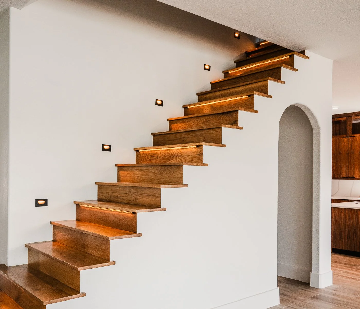 Wooden staircase with integrated lighting on a white wall in a modern home interior