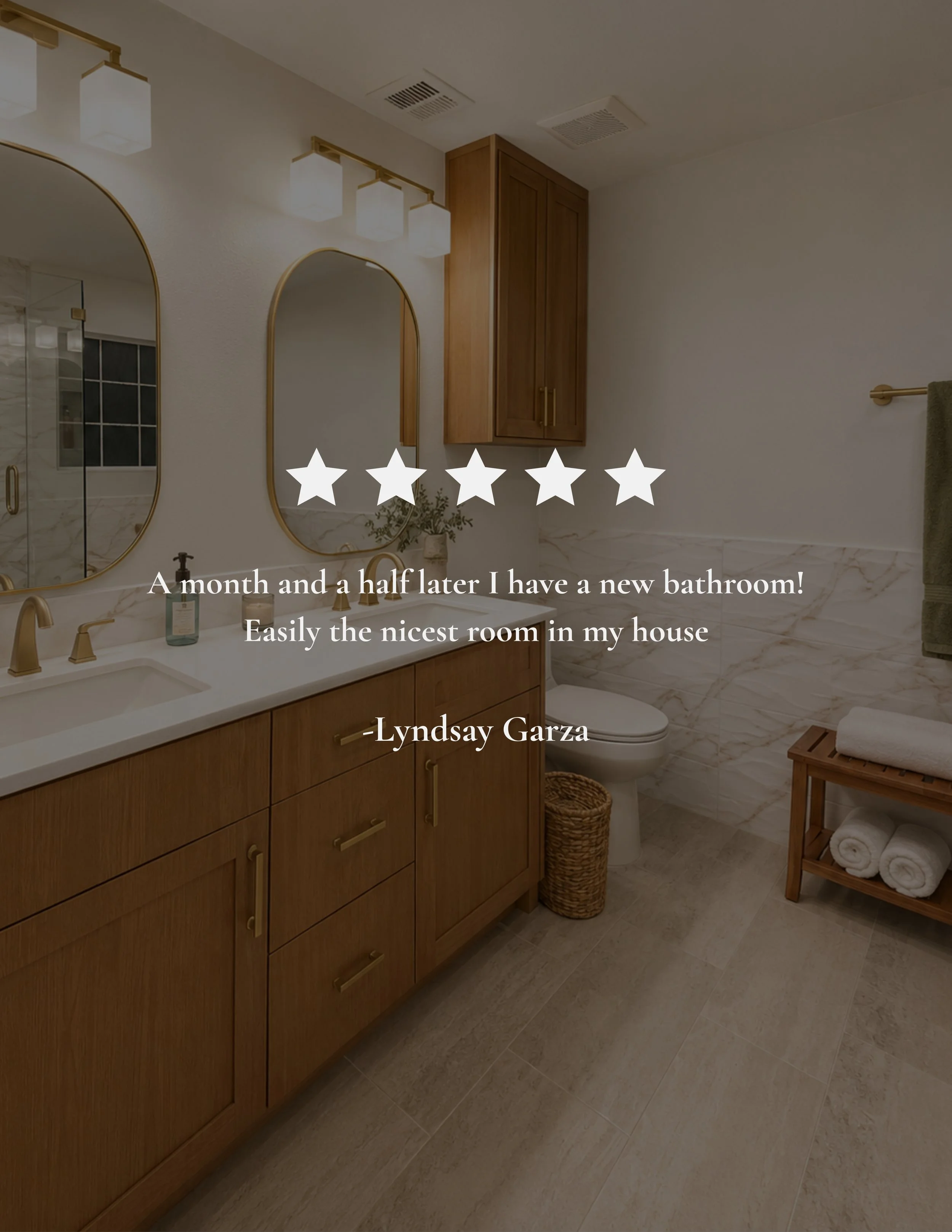 A modern bathroom with wood cabinetry, two oval mirrors with gold frames, a white countertop with gold fixtures, and a shower area with marble tiles and a glass door. There are wall-mounted lights above the mirrors, a wall cabinet, a small plant in a