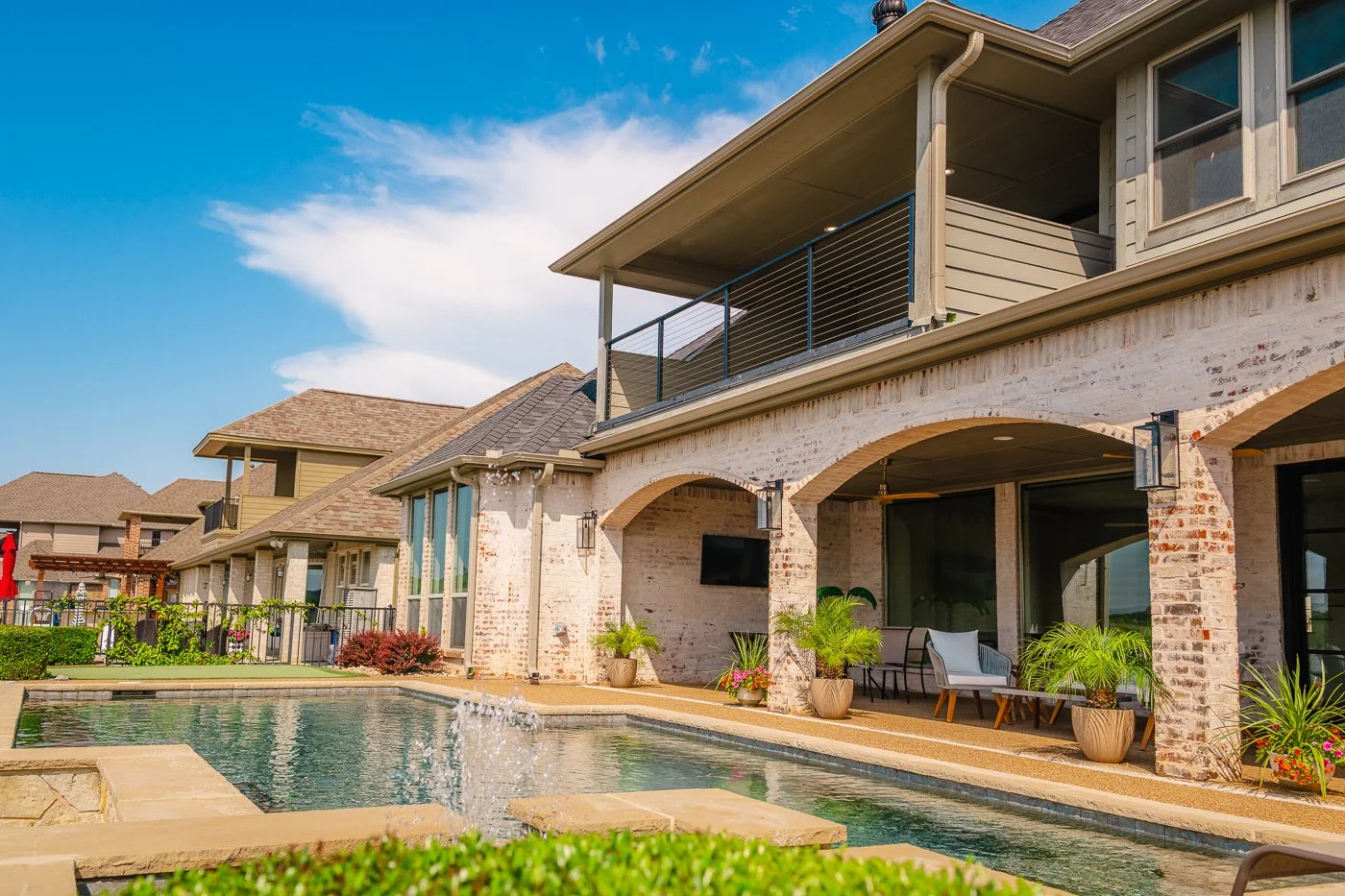 A backyard view of a modern house with a swimming pool, outdoor seating area, and potted plants.
