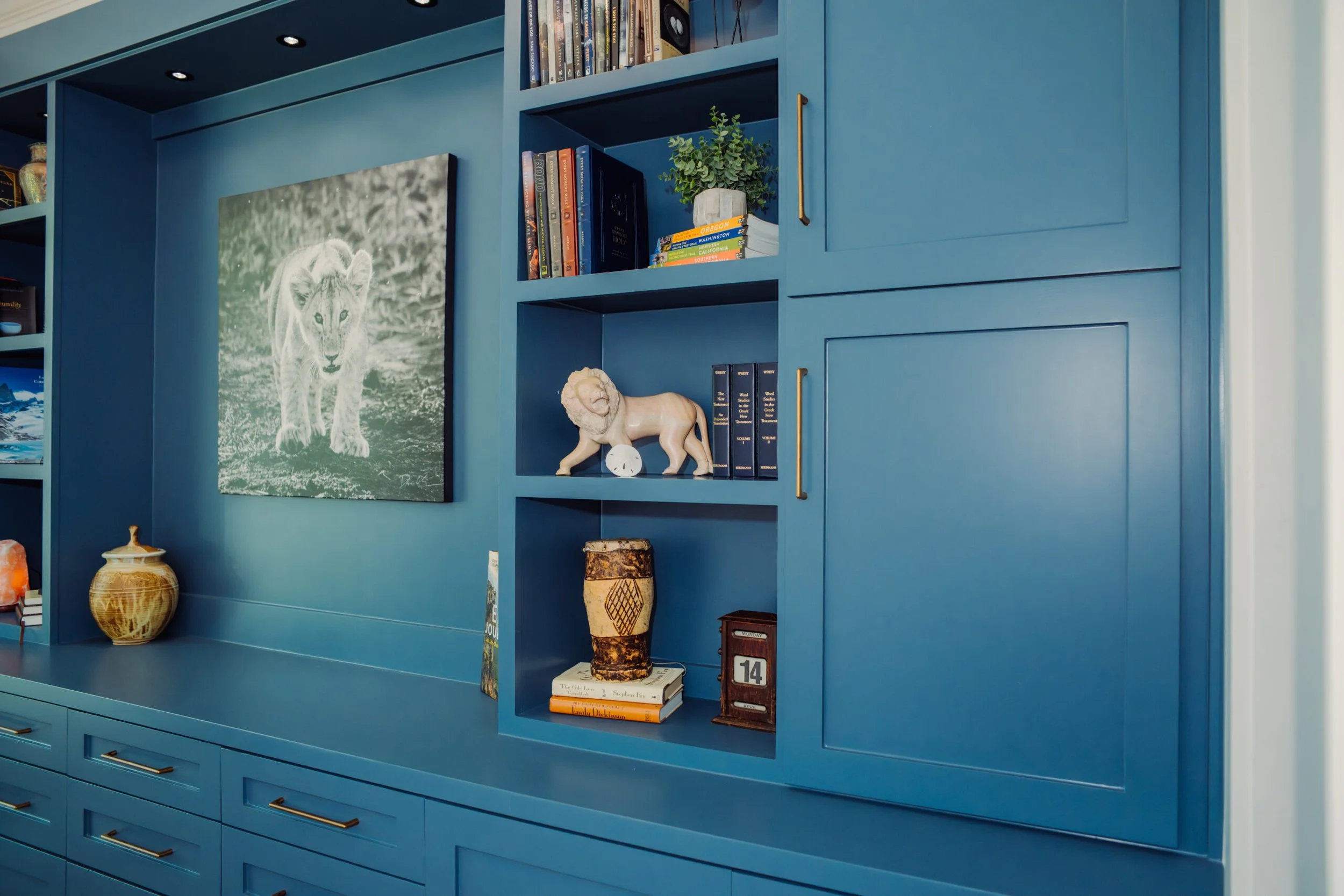 Blue bookshelf with books, potted plant, lion sculpture, vase, and decorative items