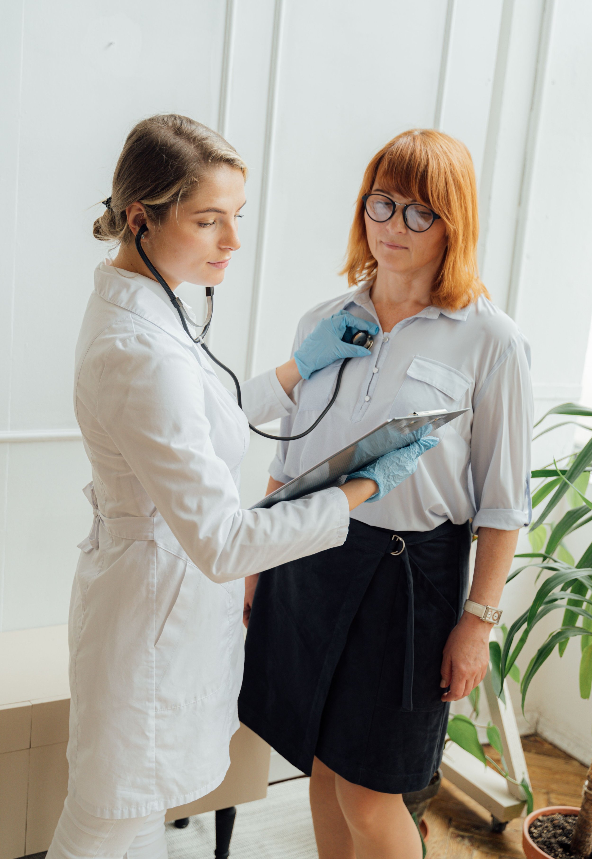 A female doctor using a stethoscope on a female patient.
