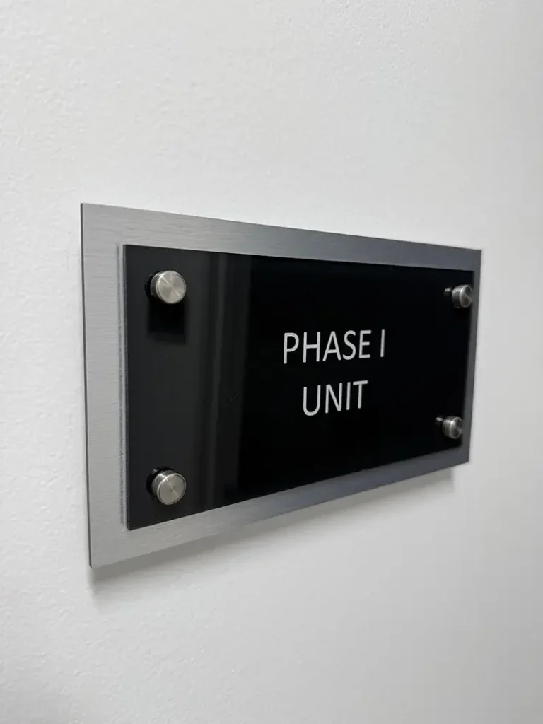 Black sign on wall with white text reading 'PHASE I UNIT'.